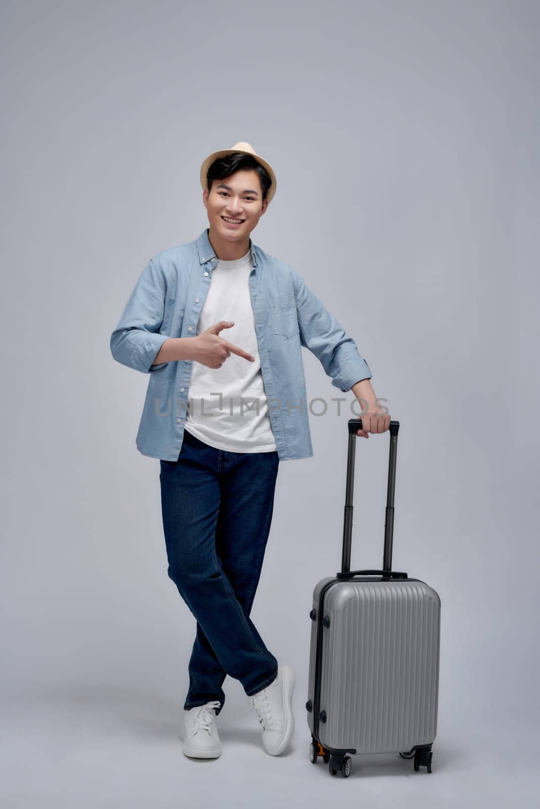 Full length profile shot of a guy walking and pulling a suitcase isolated on white background by makidotvn