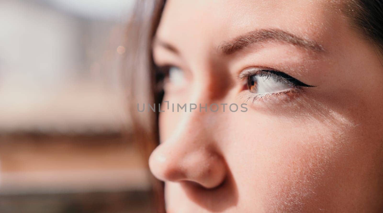 Happy young smiling woman with freckles outdoors portrait. Soft sunny colors. Outdoor close-up portrait of a young brunette woman and looking to the camera, posing against autumn nature background by panophotograph