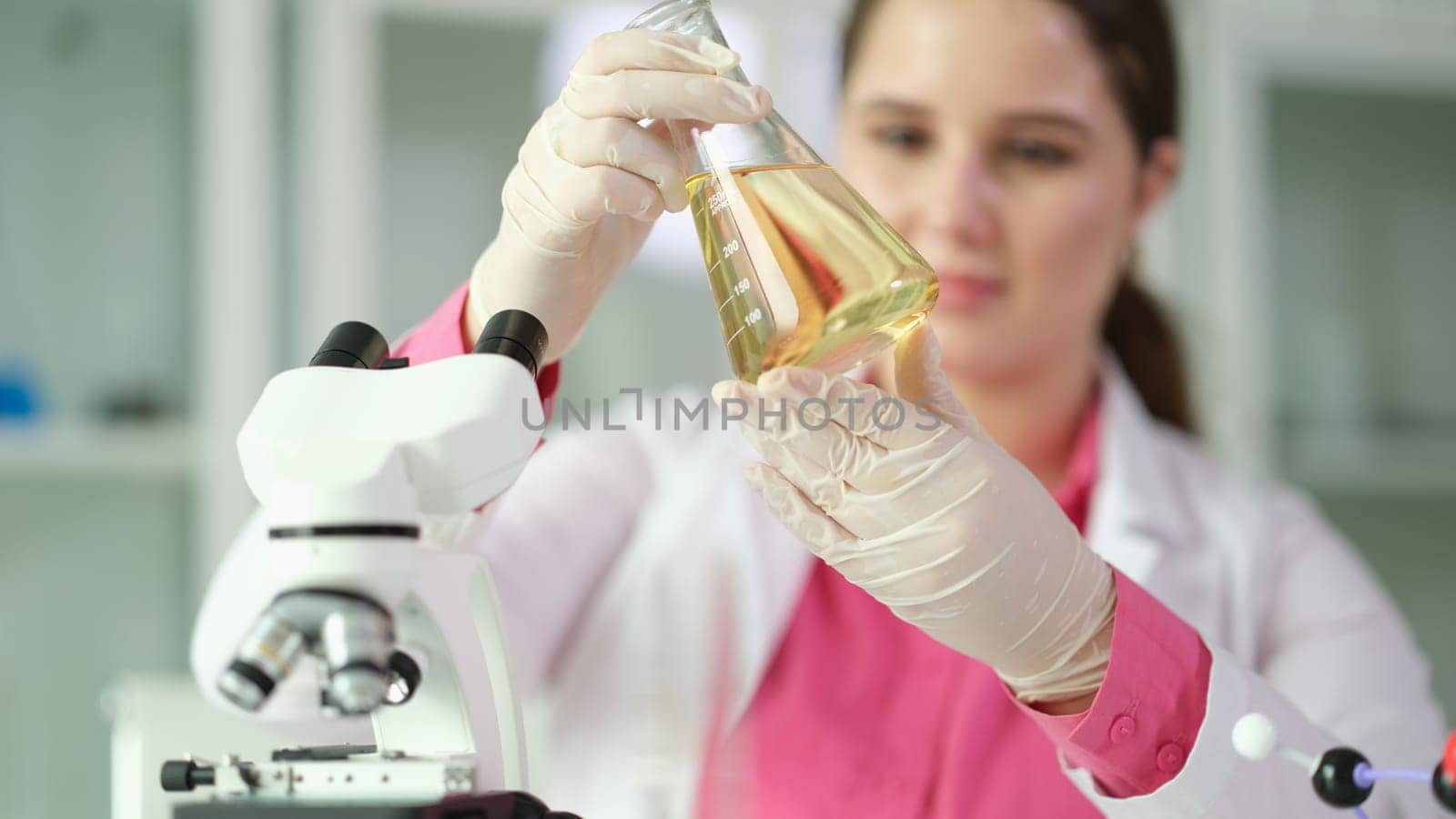 Researcher scientist student holding flask with yellow liquid. Studying properties of oil and oil products