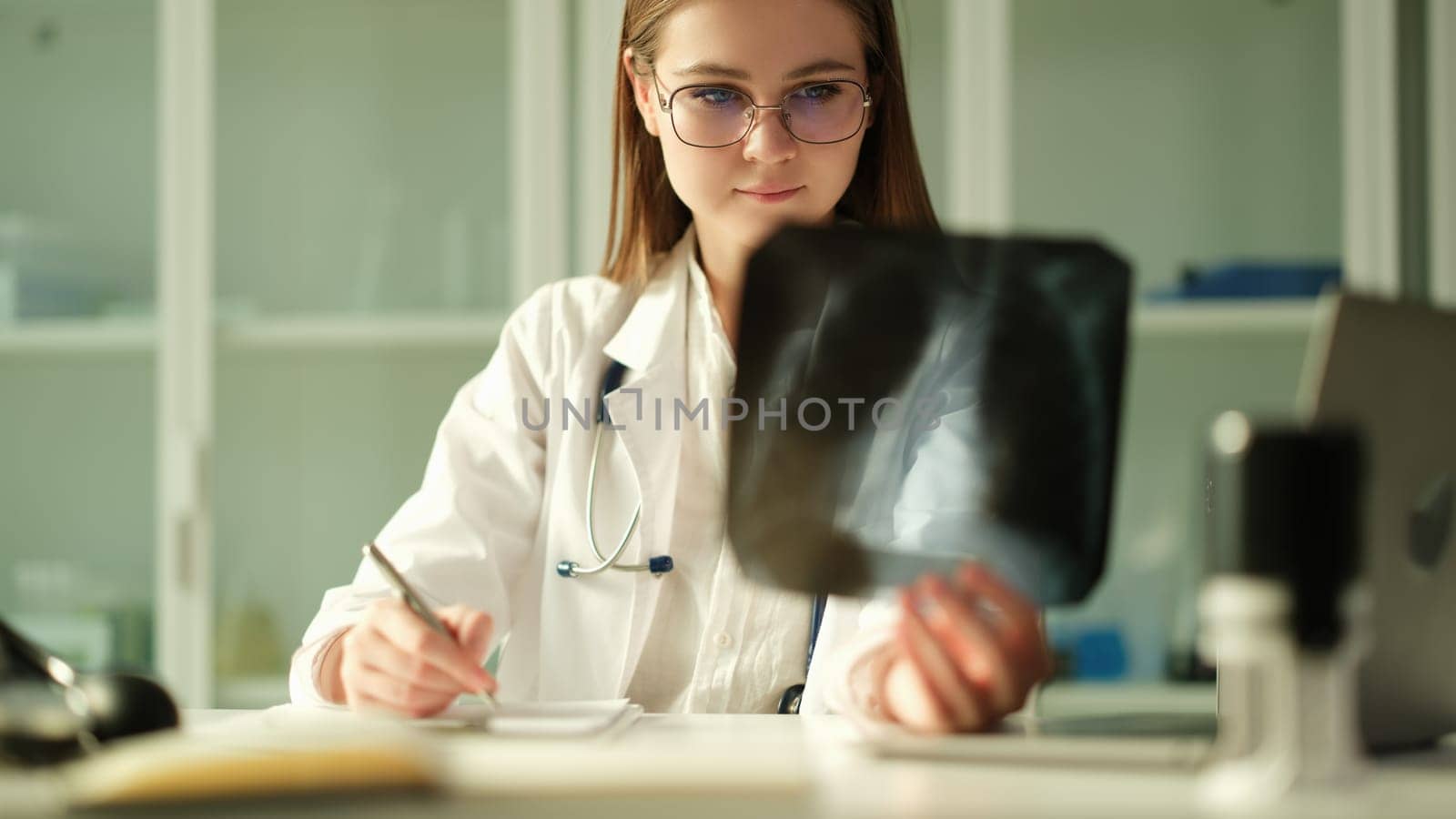 Concentrated woman surgeon traumatologist looks at x-rays examines fracture or fluorography. Doctor considers problem solving diagnostics and medical care concept