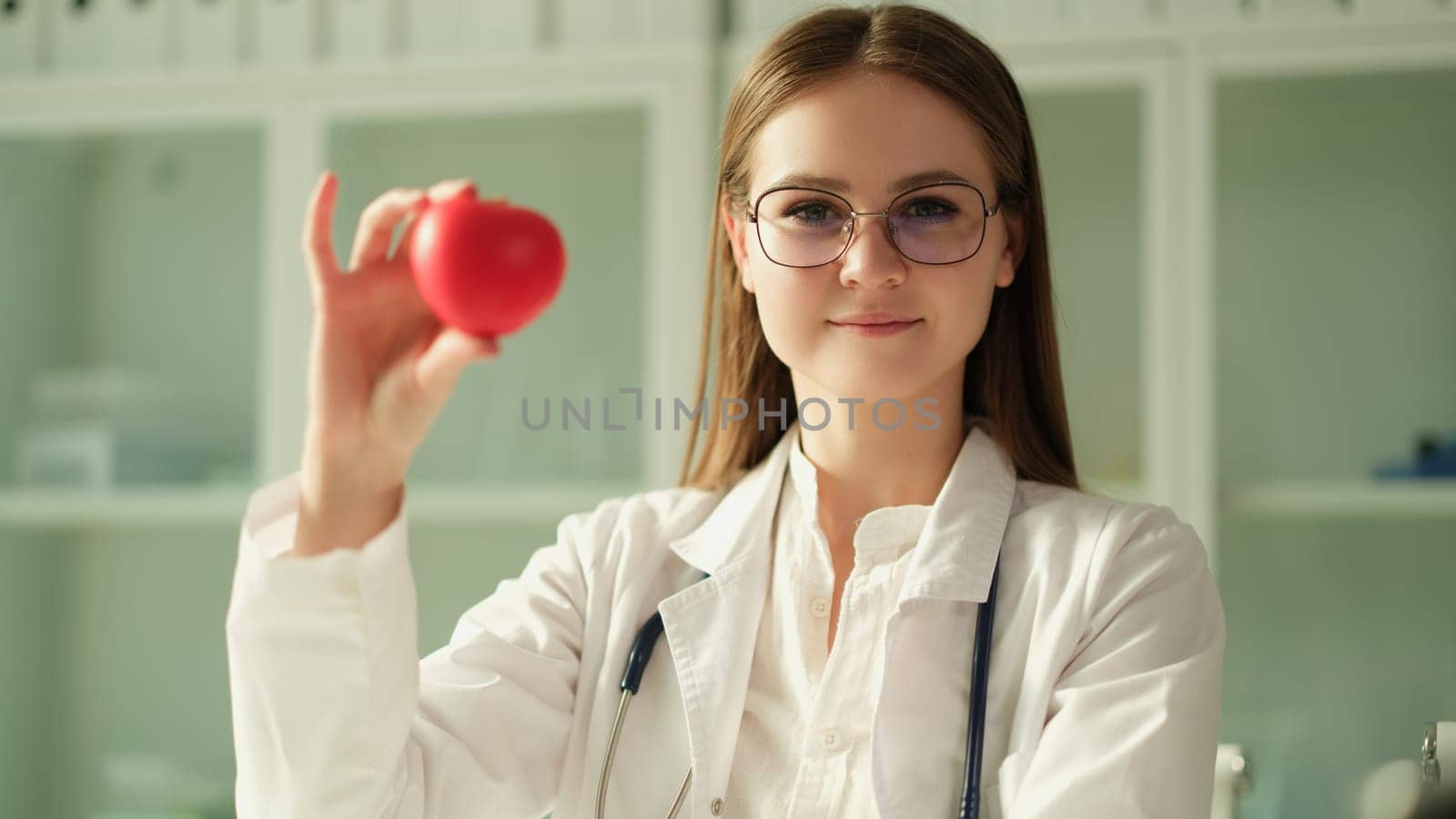 Happy female cardiologist doctor holding heart figure in hand by kuprevich