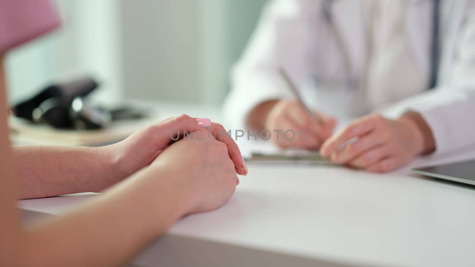 Woman sitting at table, visiting doctor in clinic and sharing problem by kuprevich