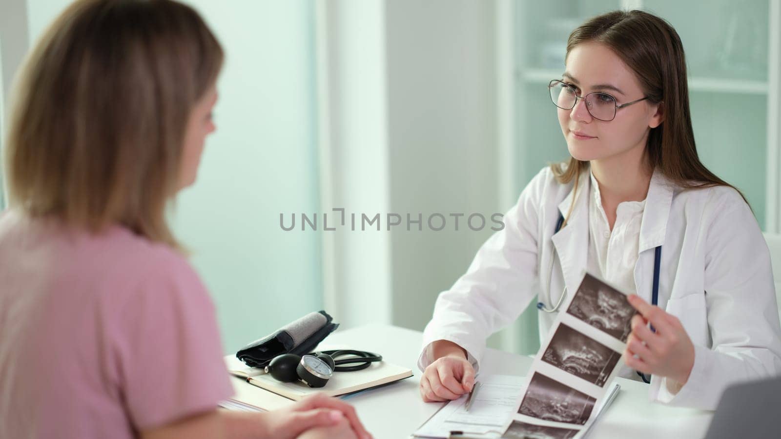 Gynecologist doctor communicates with patient and examines results of ultrasound examination of internal organs in clinic. Examination and X-ray of fetus