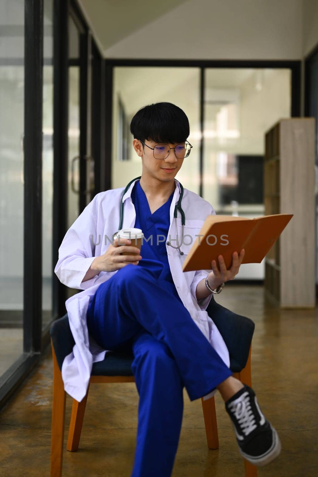 Portrait of medical student man wearing headphone and reading book. Medical internship concept.
