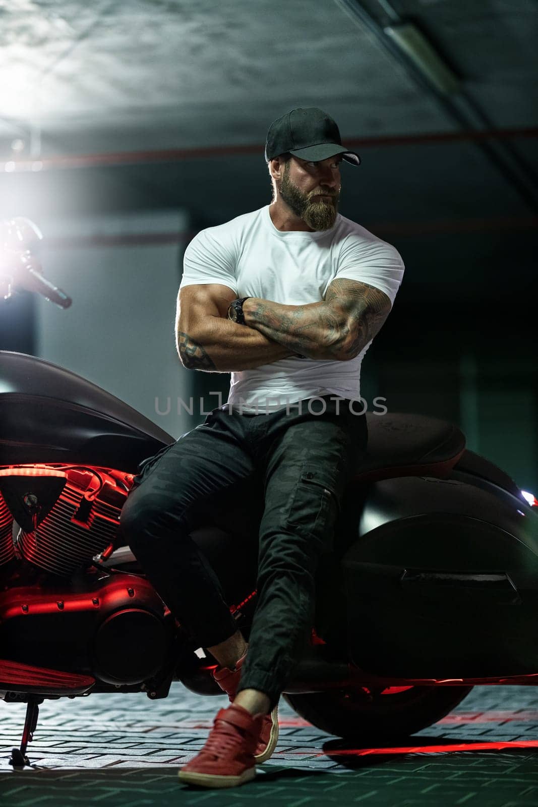 Athletic bearded biker man riding motorbike isolated on indoor parking by but_photo