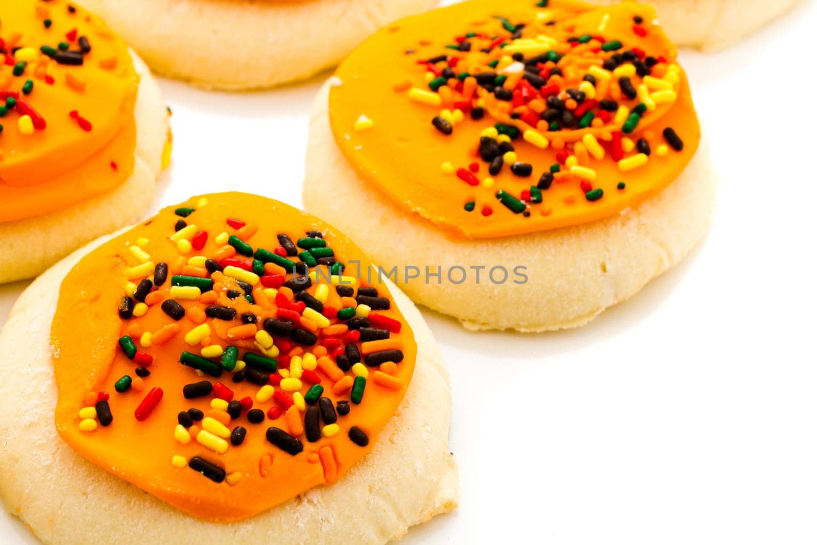 Sugar cookies with orange icing and spkinkles.