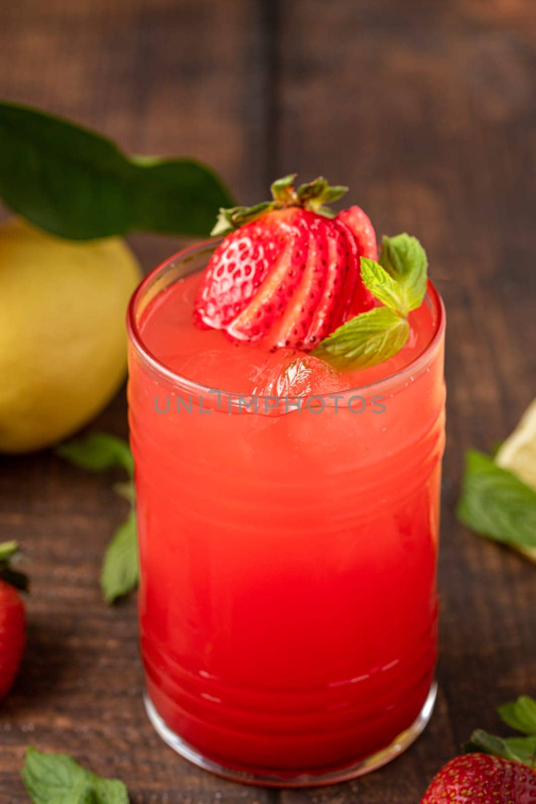 Iced strawberry lemonade in glass glass on wooden table by Sonat