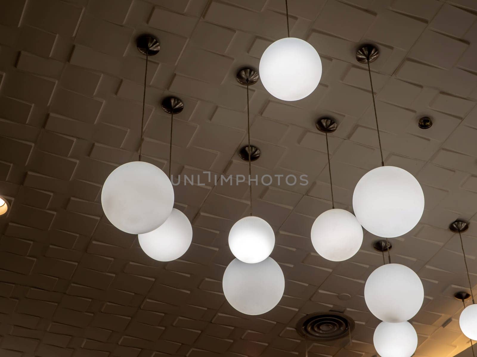 Round lamp hanging alternating high and low decorating the ceiling by Satakorn