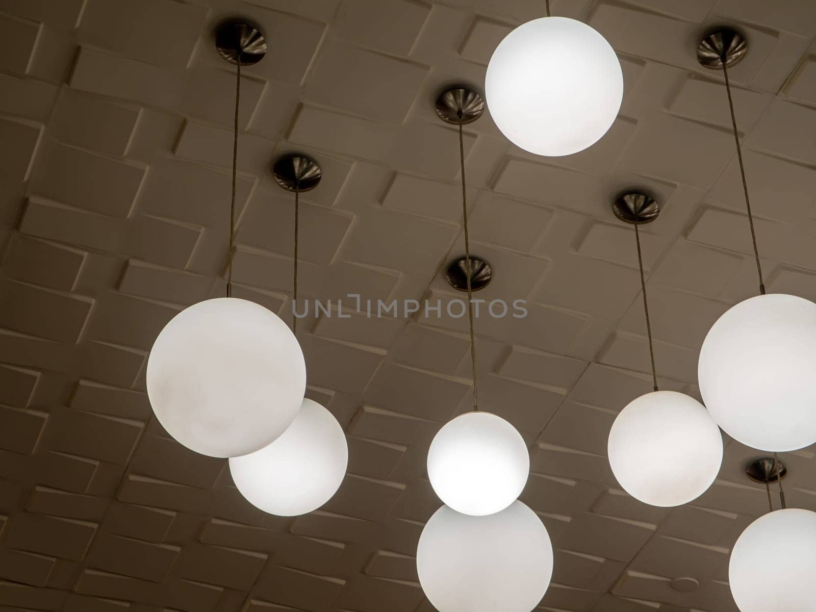 Round lamp hanging alternating high and low decorating the ceiling by Satakorn