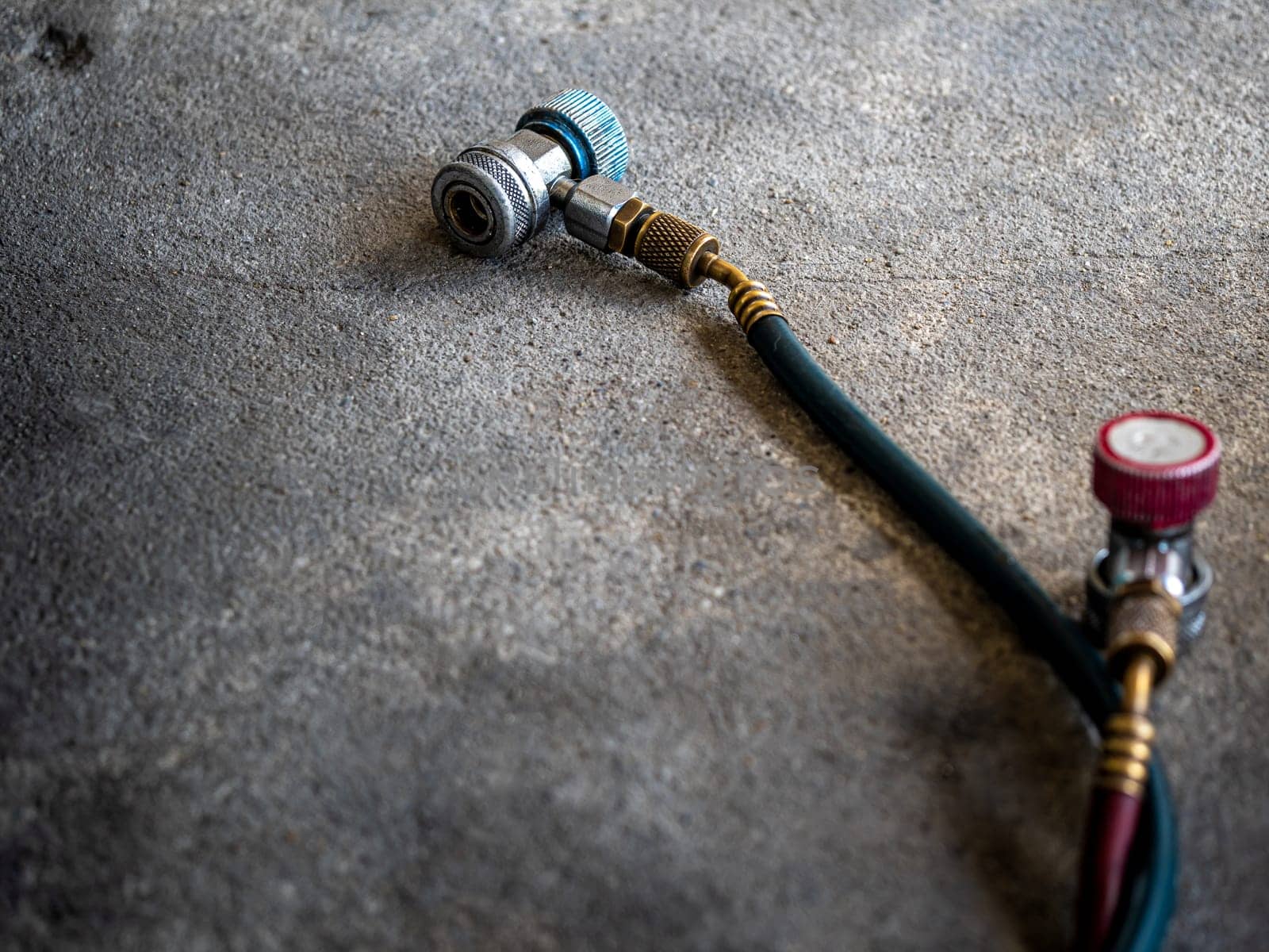 Air Conditioner Charging Hose on the rough concrete flooring by Satakorn