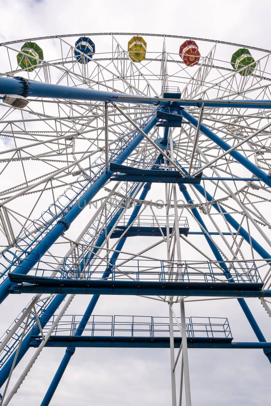 Big Ferris wheel against the sky on a cloudy day. Cabins in different colors. Place of entertainment and recreation.ferris wheel against a blue sky. High quality photo