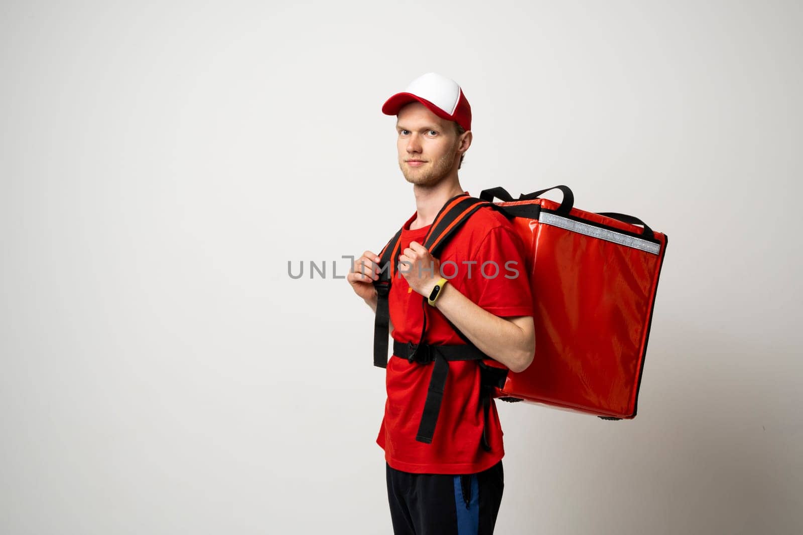 Delivery employee man in red uniform with athermal food bag backpack work as a courier. by vovsht