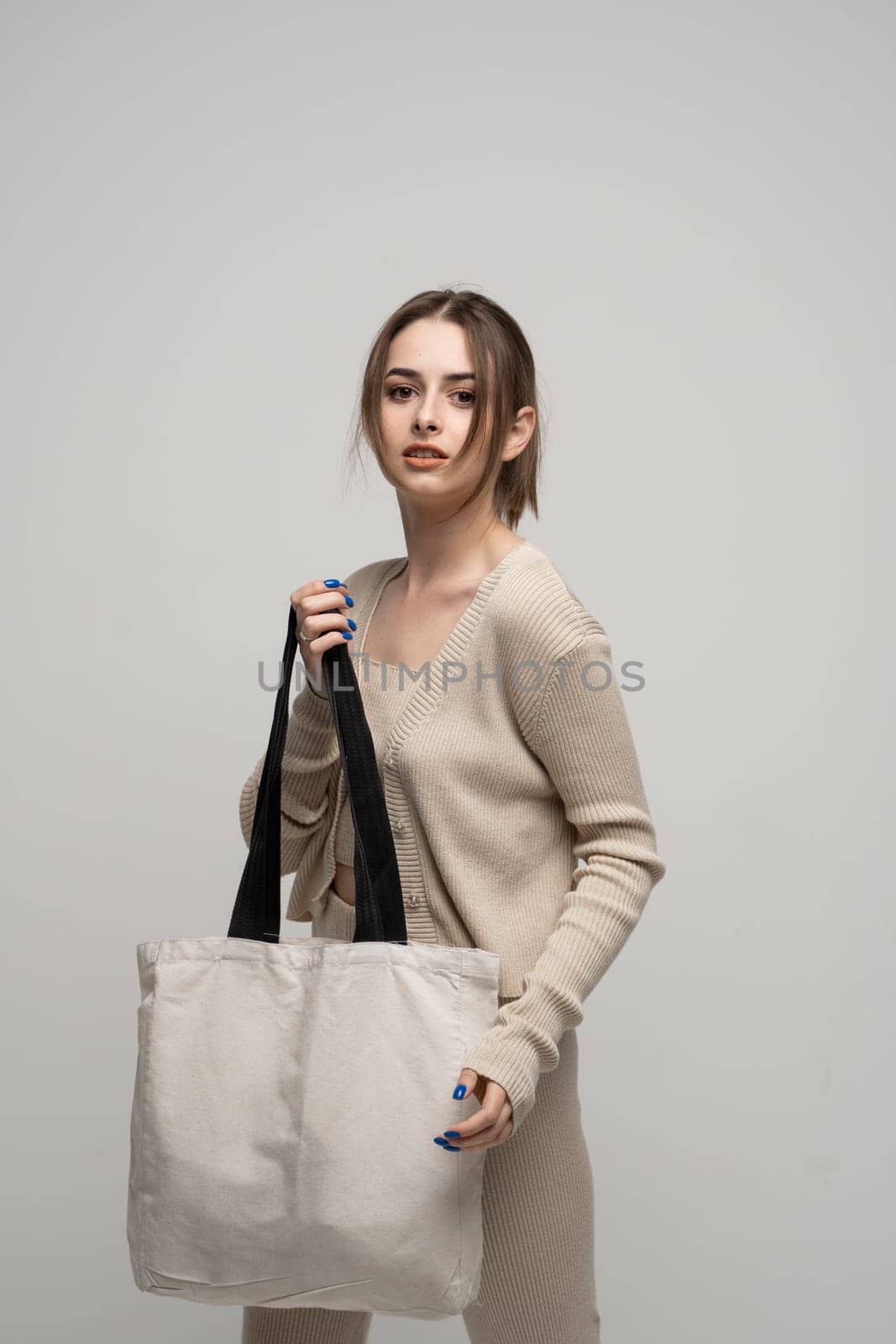 Brunette young girl holding linen shopping bag, mock up. Lady holding flax shopper handbag. Fashion and ecology concept