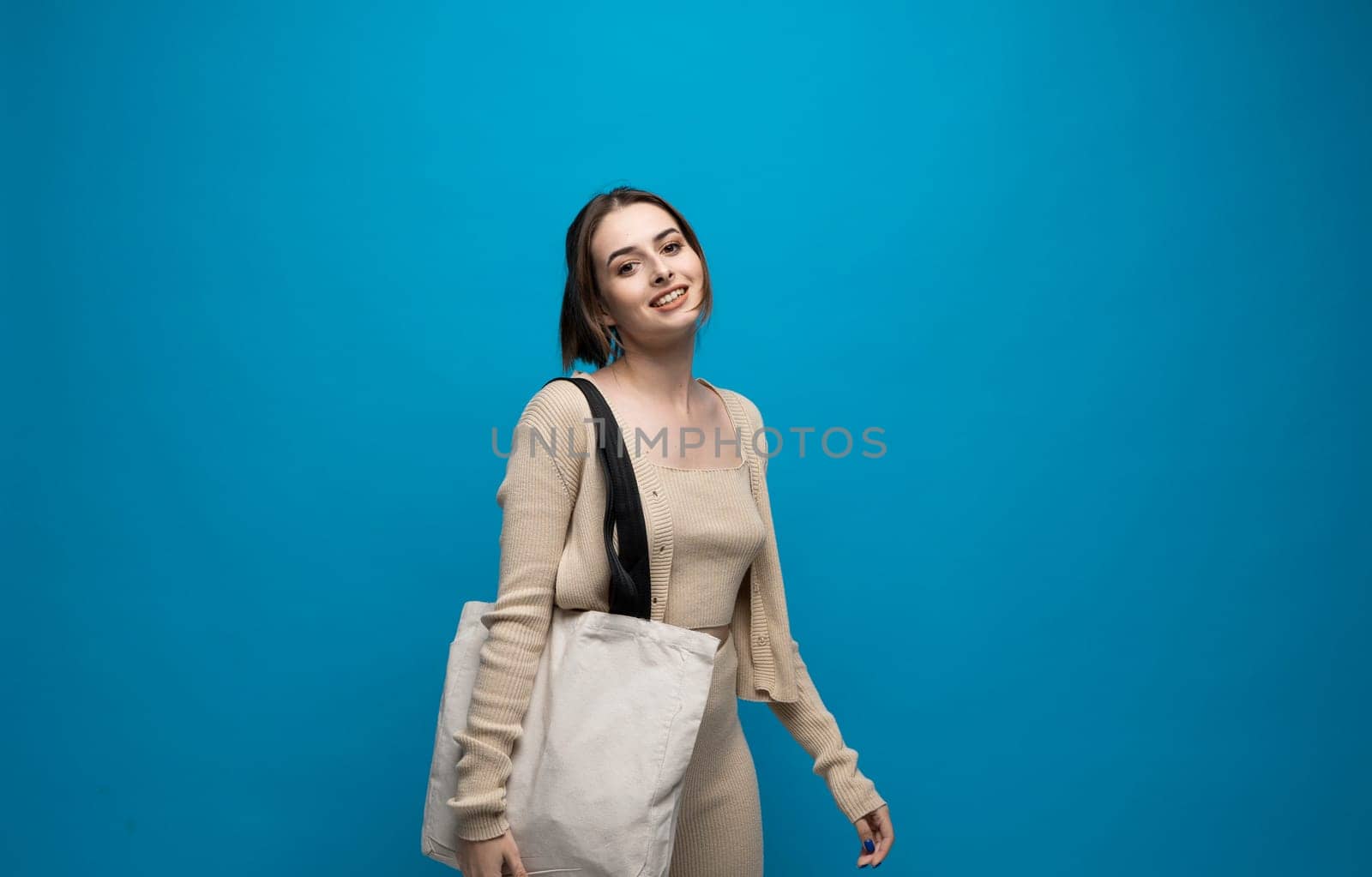 Brunette young girl holding linen shopping bag, mock up. Lady holding flax shopper handbag. Fashion and ecology concept. by vovsht