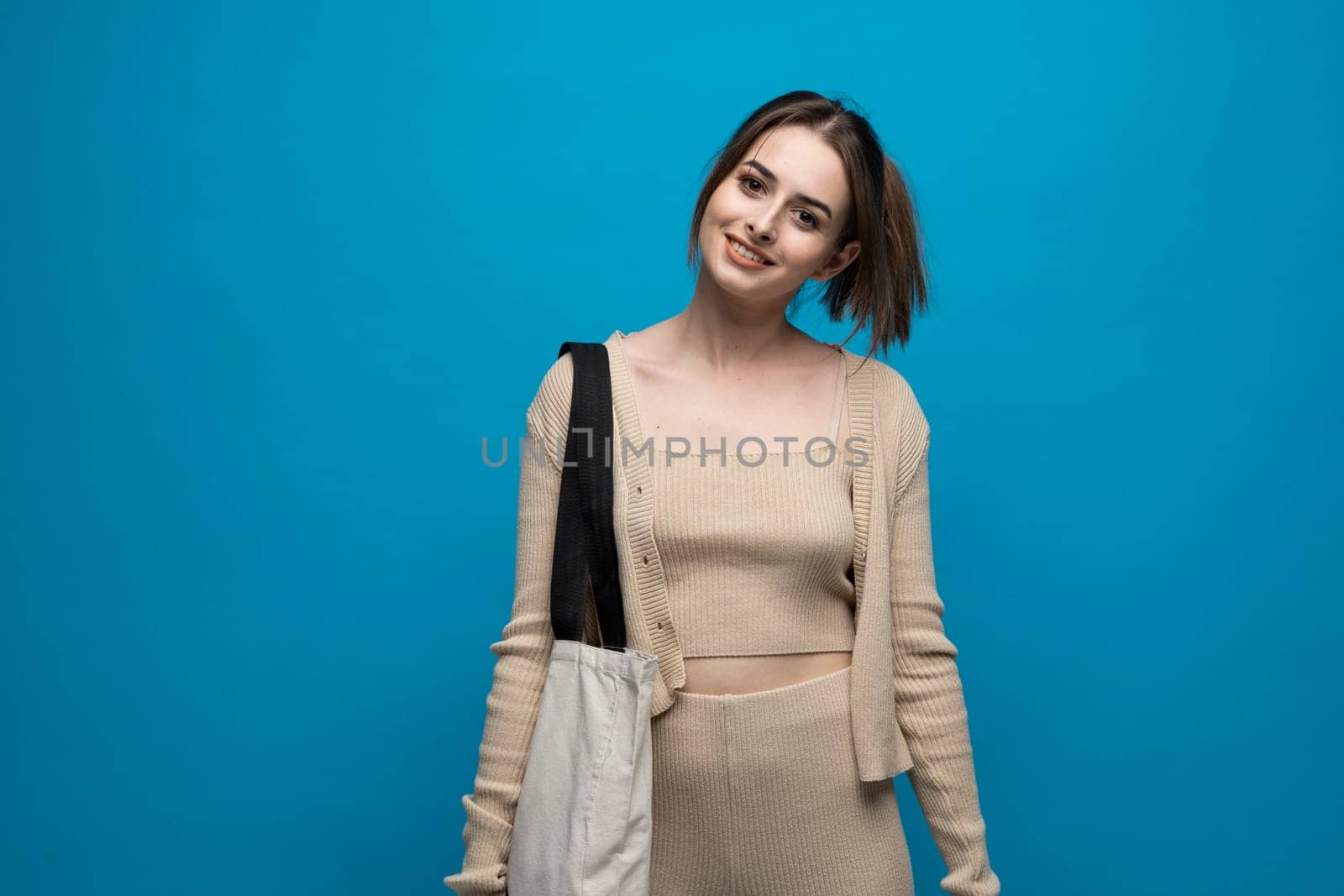 Brunette cheerful millennial woman holding white eco bag standing over white studio background. Concept of recycle for better environment. No plastic. Fashion and ecology concept. by vovsht