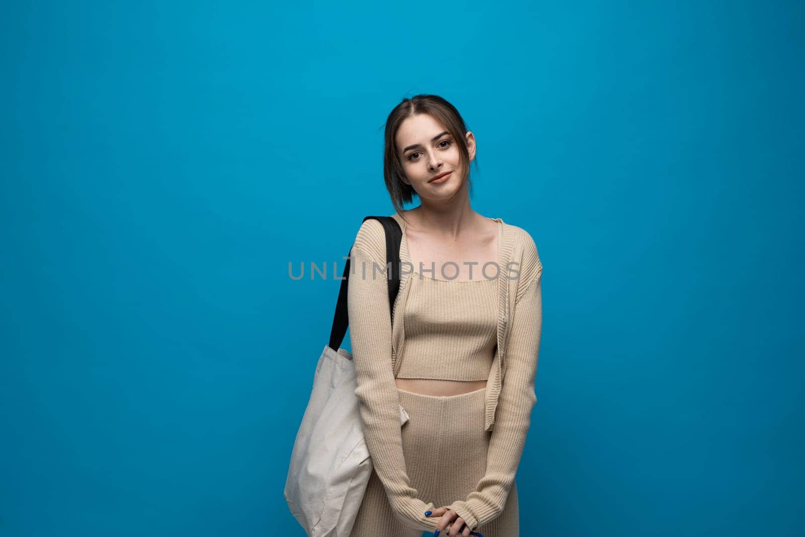 Brunette cheerful millennial woman holding white eco bag standing over white studio background. Lady holding flax shopper handbag. Fashion and ecology concept