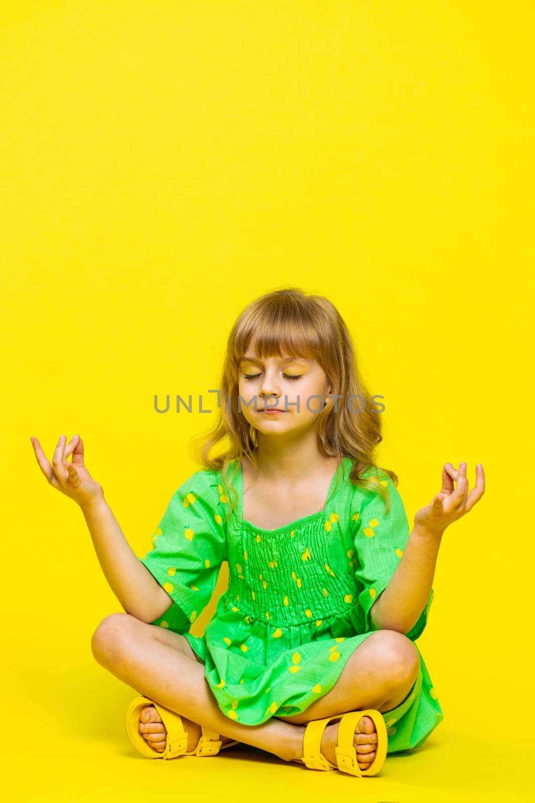 Keep calm down. Blonde child girl kid breathes deeply with mudra gesture, eyes closed, meditating with concentrated thoughts, peaceful mind, relaxing, taking a break, rest. Preteen children. Vertical