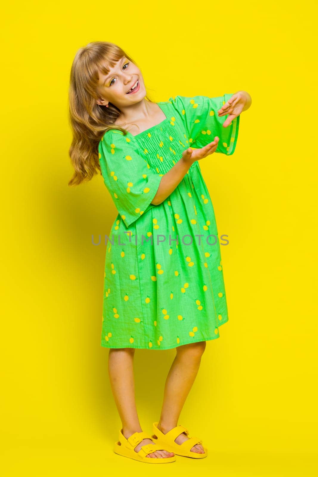 Child girl kid showing wasting, throwing money around, more tips, big profit, winning lottery jackpot, successful shopping payment purchase, cashback. Preteen children on yellow background. Vertical