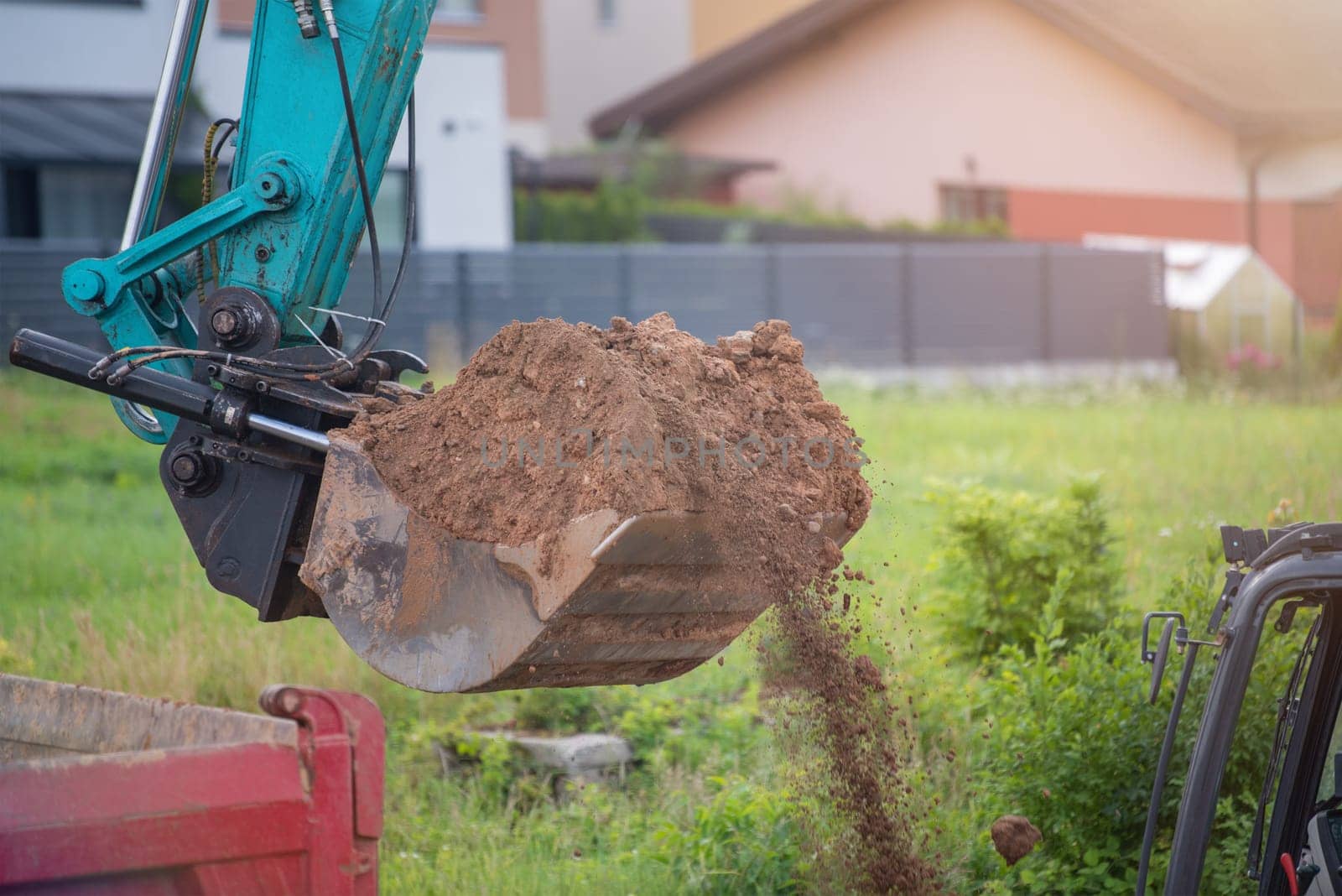 The process of working heavy construction equipment. A big blue excavator is pouring earth into a truck. Road works, reconstruction of the road surface. by SERSOL