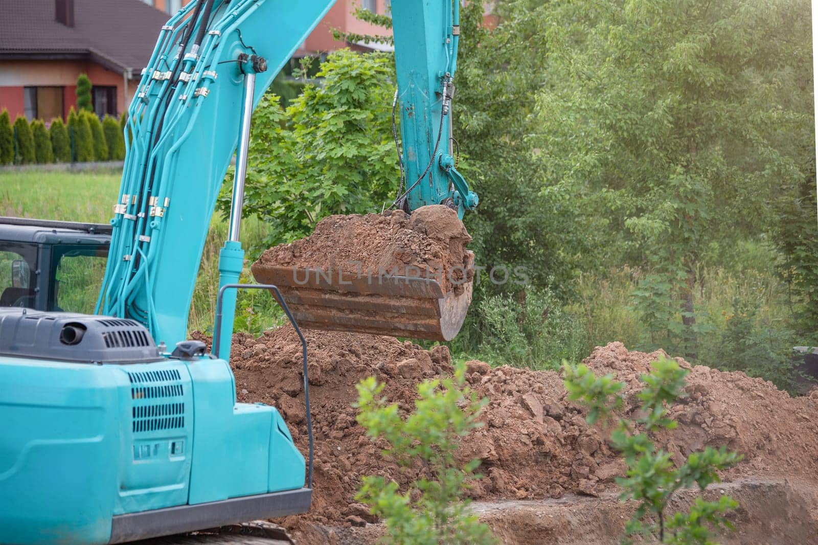 The process of working heavy construction equipment. A big blue excavator is pouring earth into a truck. Road works, reconstruction of the road surface. by SERSOL