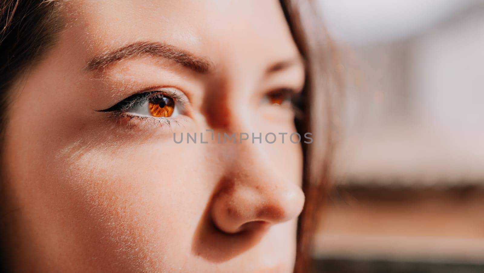 Happy young smiling woman with freckles outdoors portrait. Soft sunny colors. Outdoor close-up portrait of a young brunette woman and looking to the camera, posing against nature background.