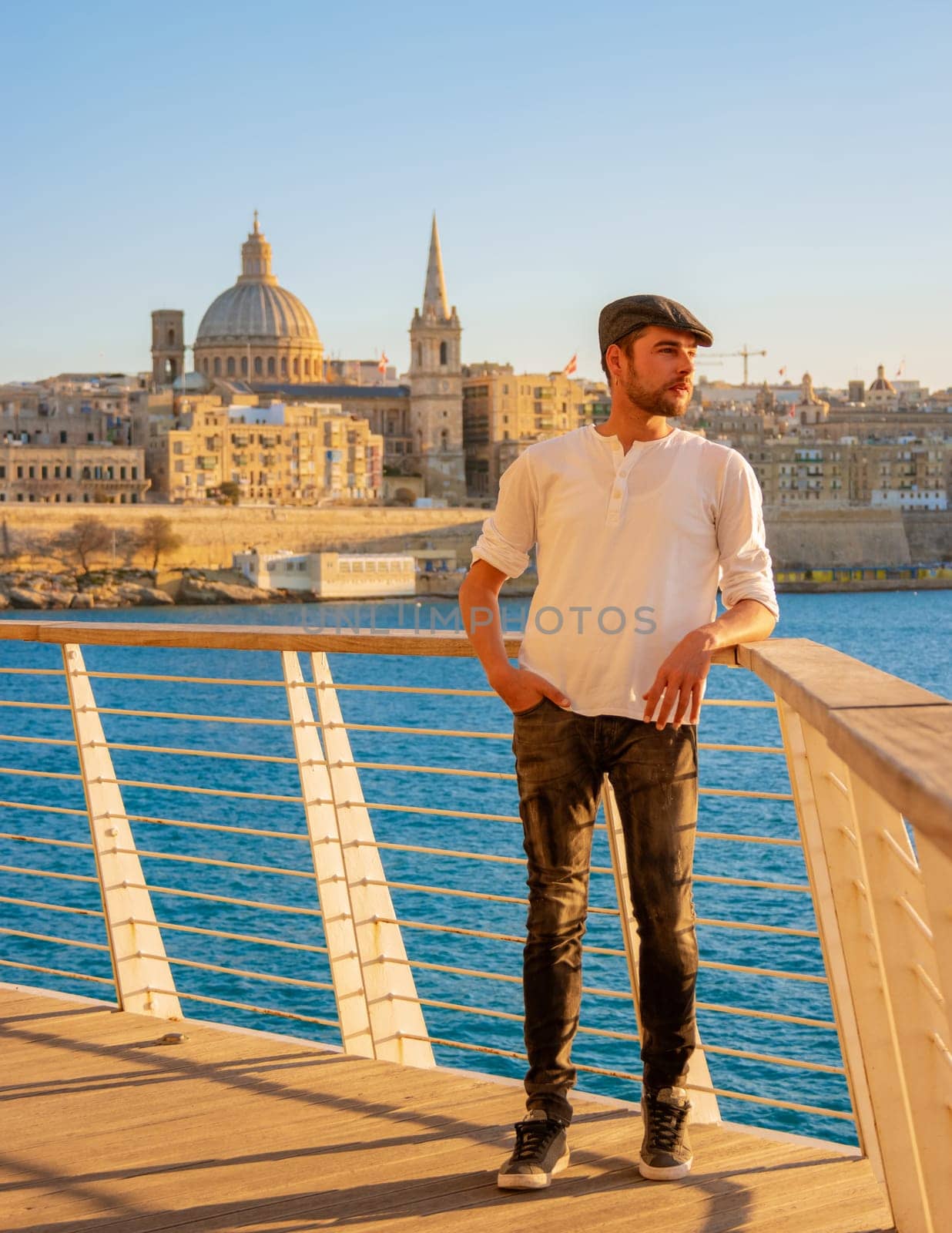 men watching the sunset during a city trip at Valletta Malta city Skyline, colorful house balcony Malta Valletta, panoramic view over Valletta Malta old town at sunset