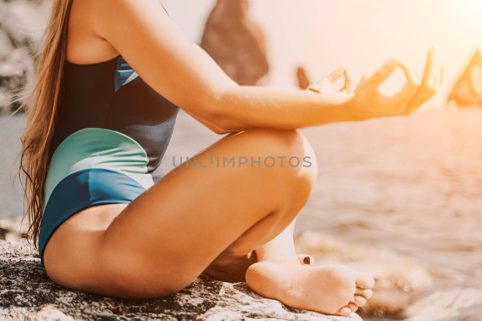 Yoga on the beach. A happy woman meditating in a yoga pose on the beach, surrounded by the ocean and rock mountains, promoting a healthy lifestyle outdoors in nature, and inspiring fitness concept. by Matiunina