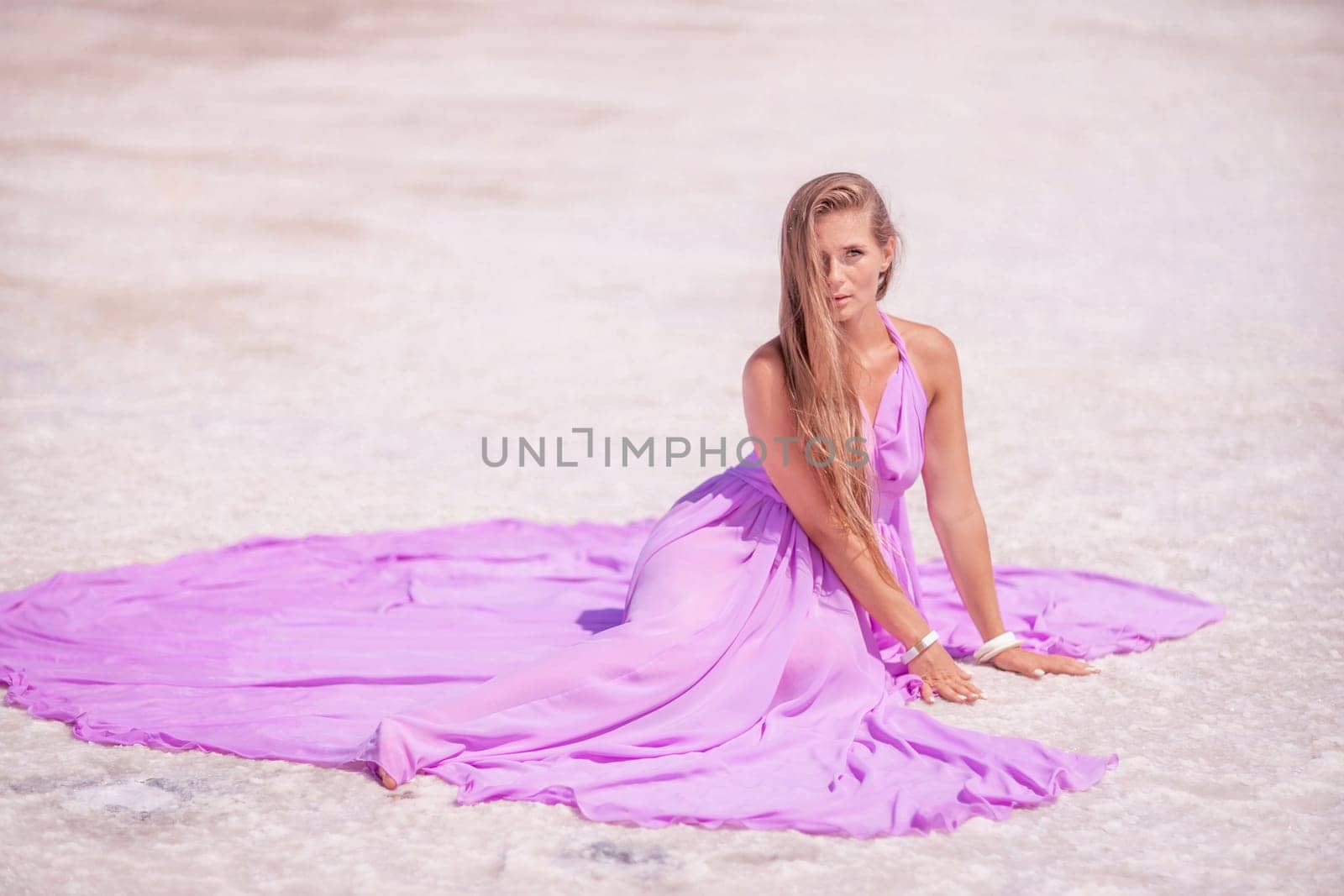 Pink lake woman. A woman in a pink dress sits on the salty shore of a pink lake and poses for a souvenir photo, creating lasting memories. by Matiunina
