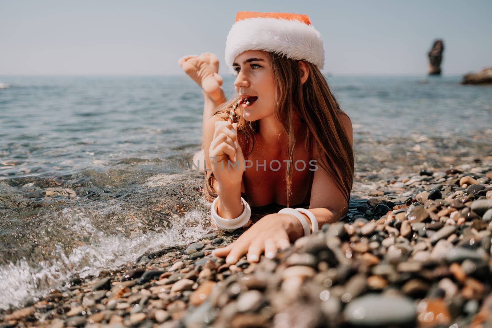 Woman travel sea. Happy tourist enjoy taking picture on the beach for memories. Woman traveler in Santa hat looks at camera on the sea bay, sharing travel adventure journey by panophotograph