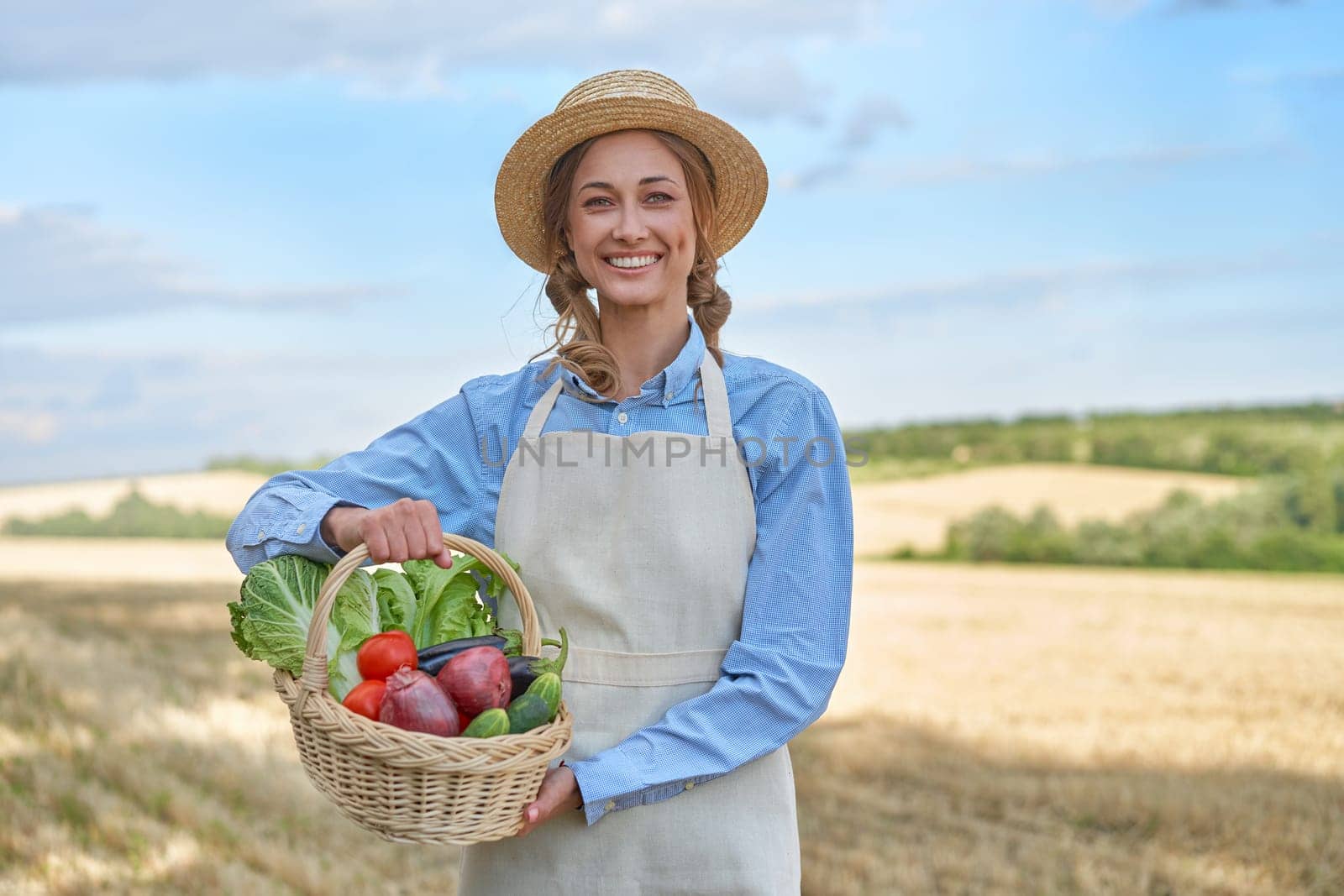 Woman farmer straw hat holding basket vegetable onion tomato salad cucumber standing farmland smiling Female agronomist specialist