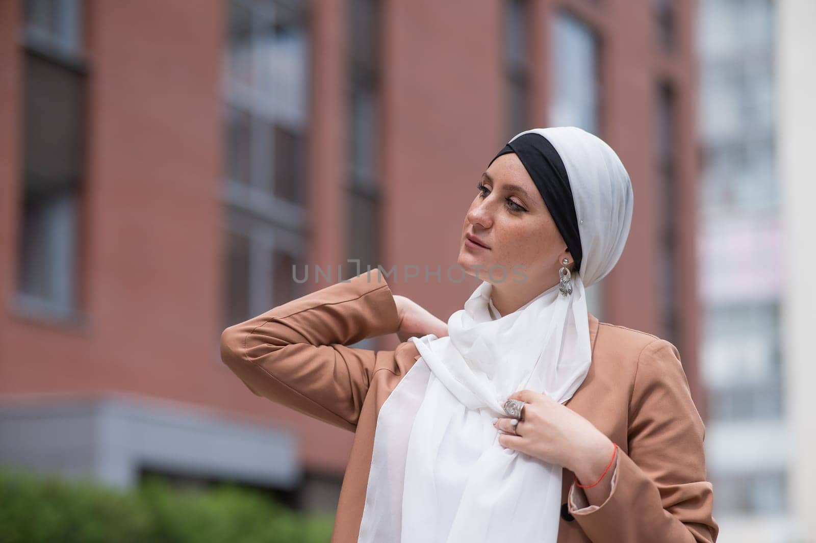 Young woman dressed in hijab and business suit walking outdoors. by mrwed54