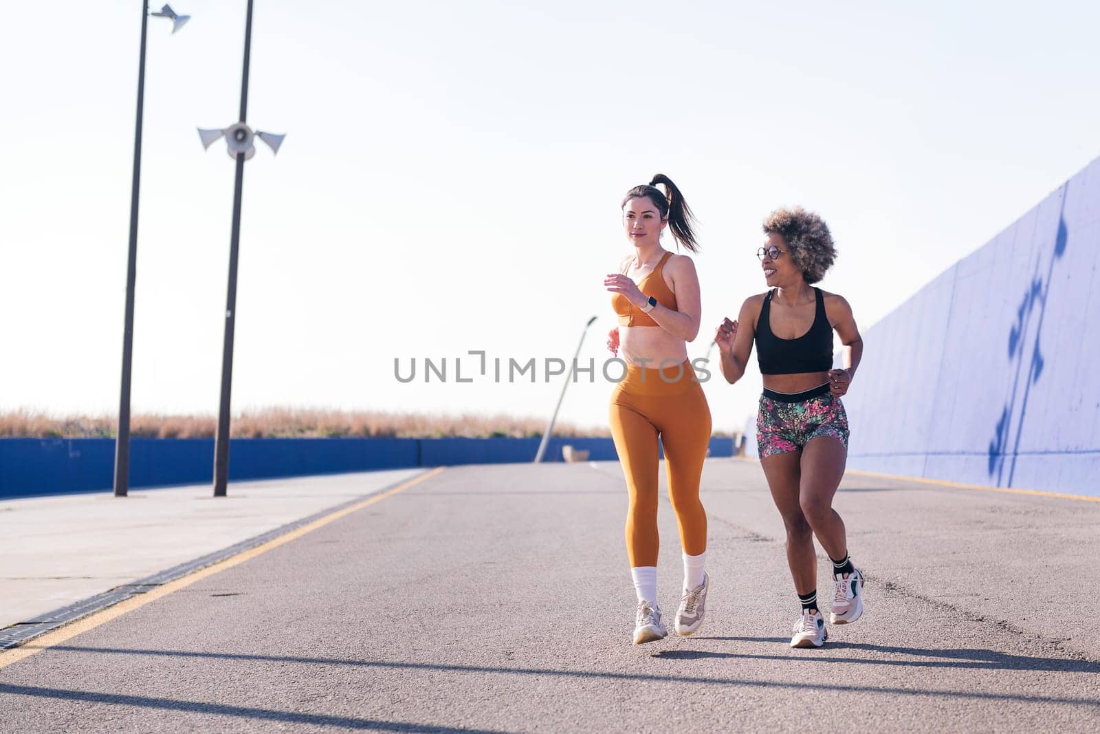 two female friends running in a athletic track by raulmelldo