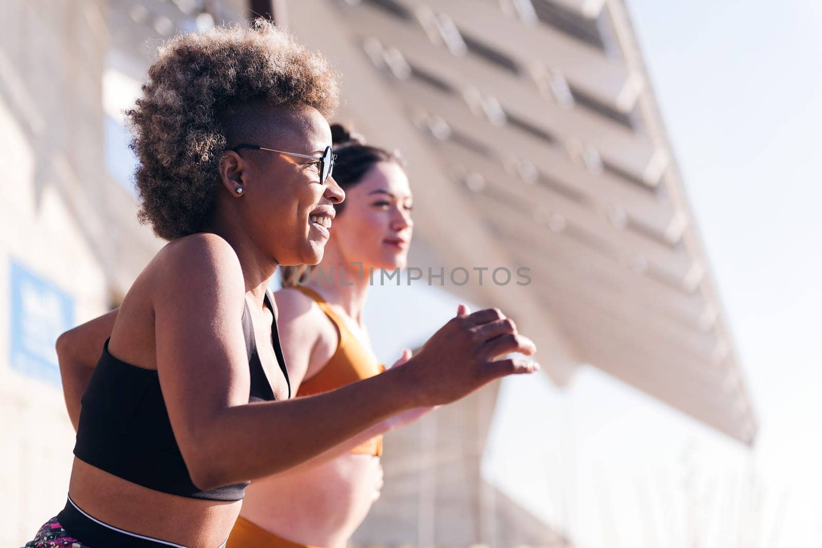 profile of two multiethnic sports women running in athletic track, concept of friendship and active lifestyle, copy space for text