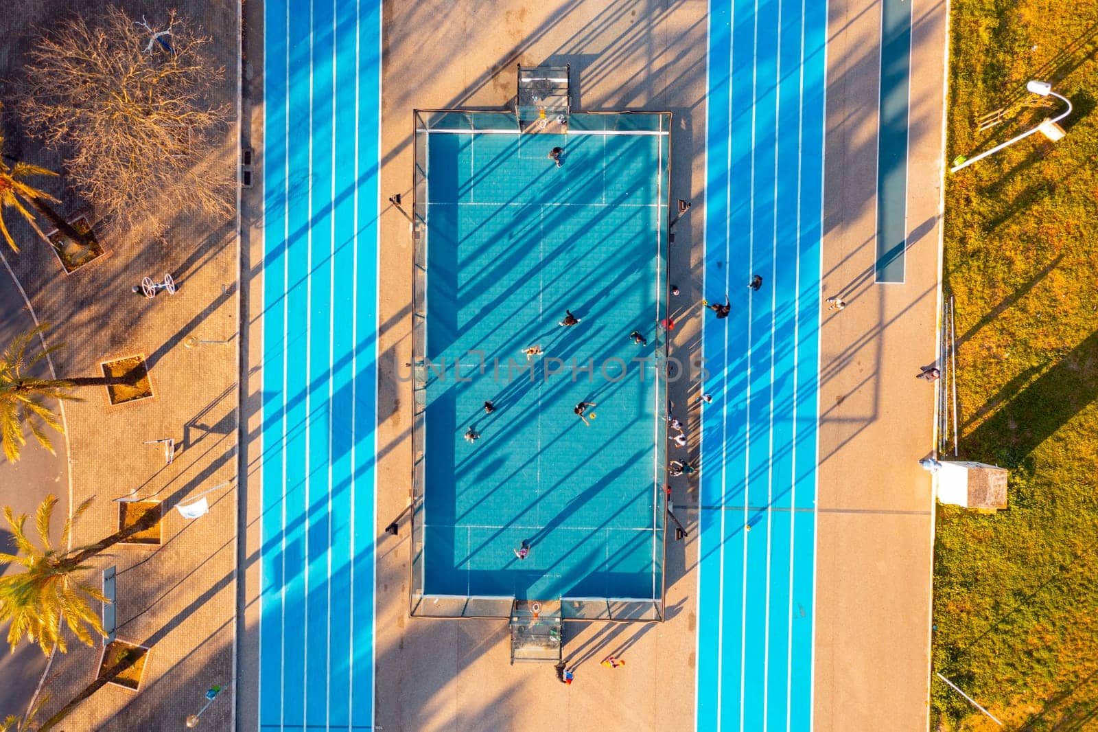 Aerial view of the city public basketball and football court with running track. Universal blue sports ground in Europe, aerial view. Game sports football, basketball