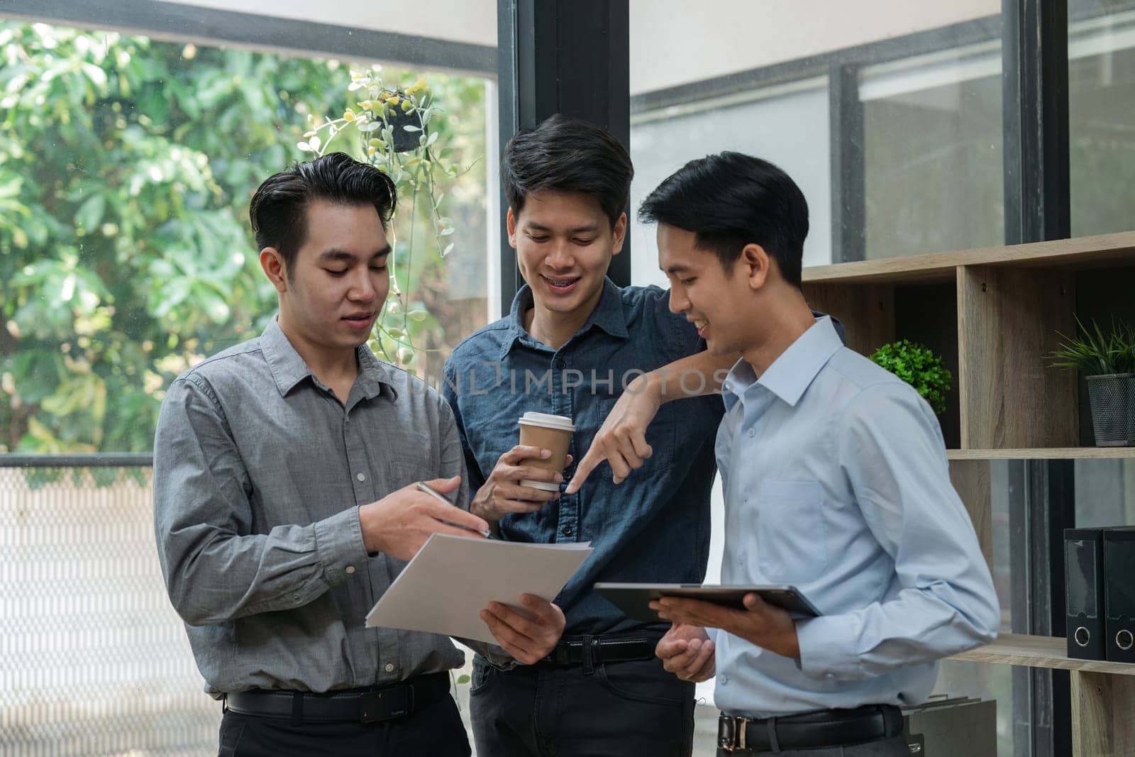 Group of young Asian business people stand talk, consult, discuss working with new startup project idea presentation analyze plan marketing and investment.