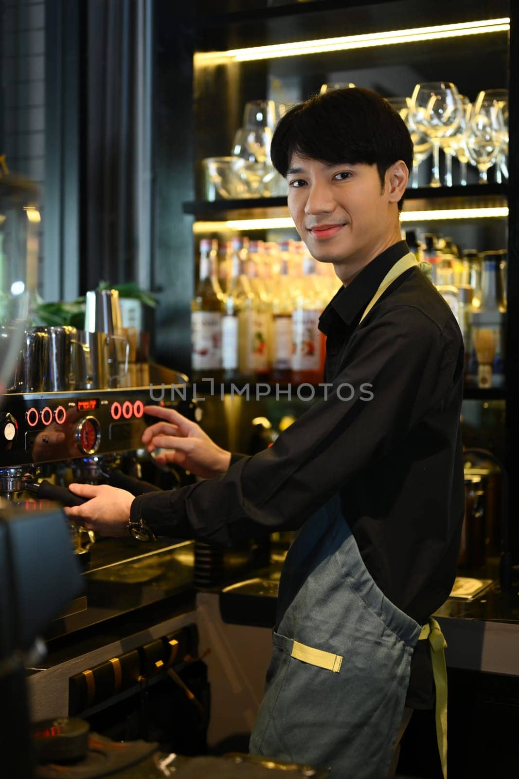 Smiling male barista preparing coffee for customer order in trendy coffee. Small business concept..