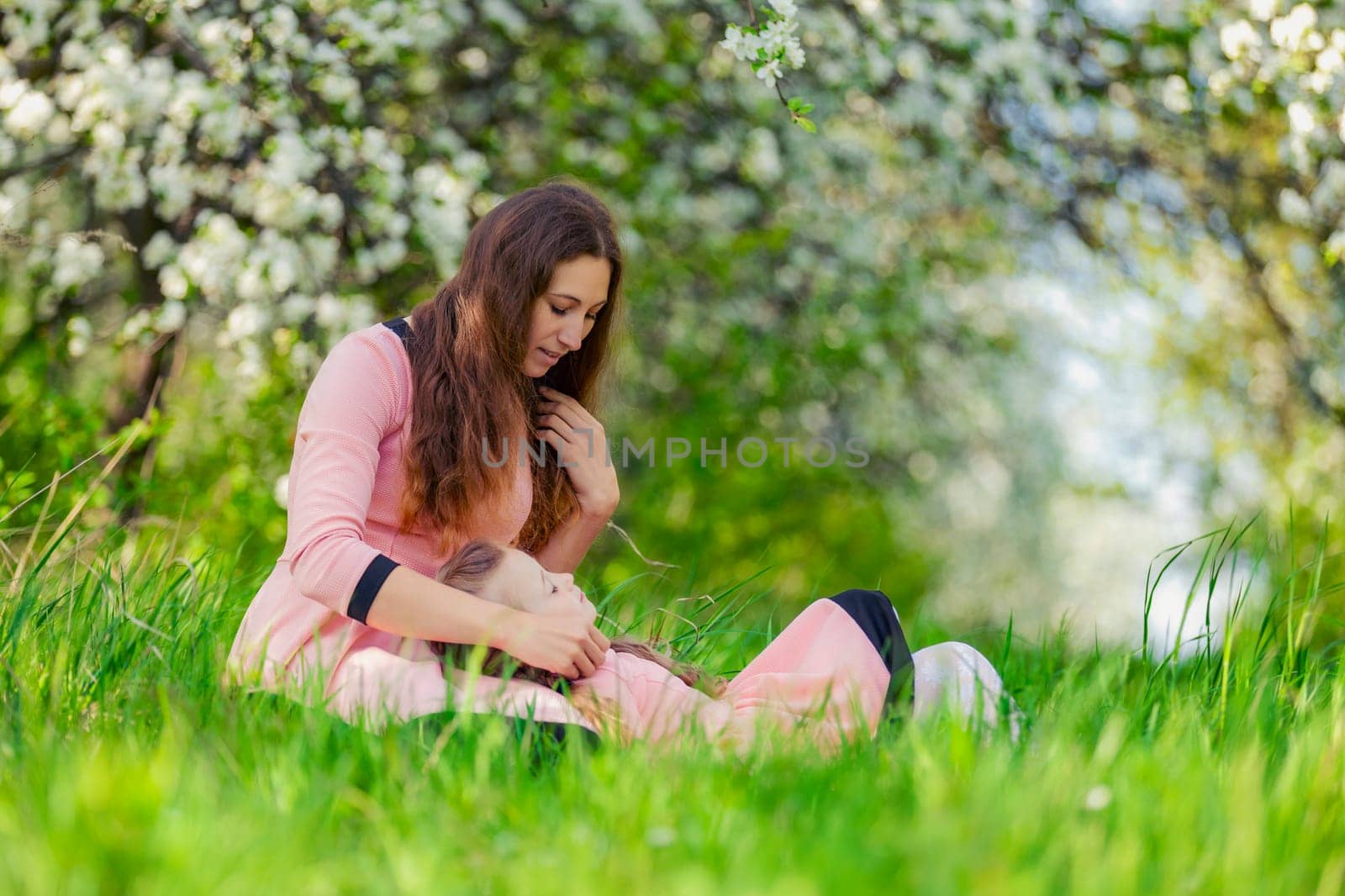 mother and daughter sit outdoors in a blooming garden