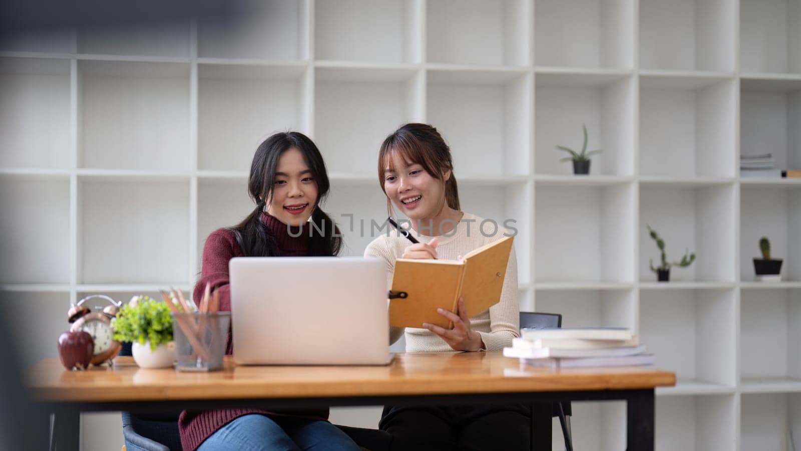 Two asian business discussing corporate strategy in teamwork, working on laptop in office at office.