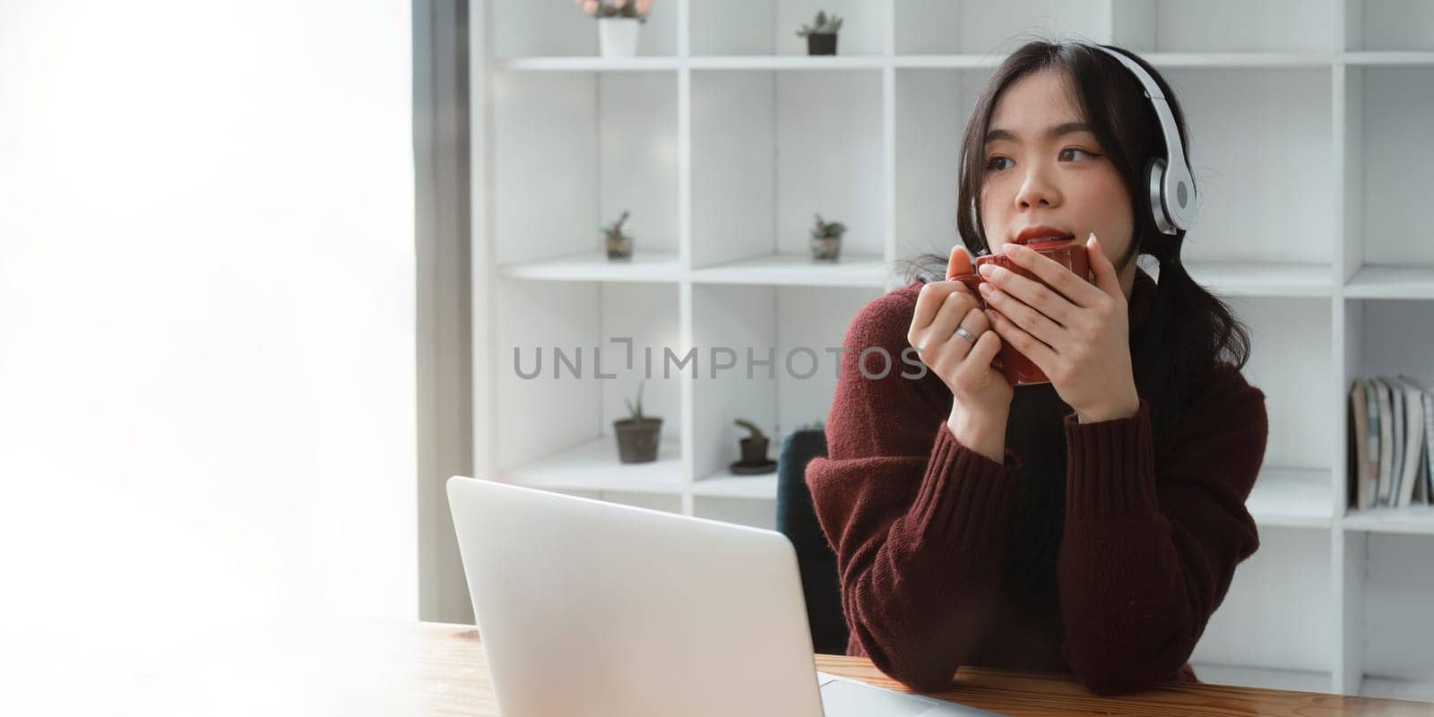 Young woman relaxing and drinking cup of hot coffee or tea using laptop computer. woman checking social apps and working. Communication and technology concept.