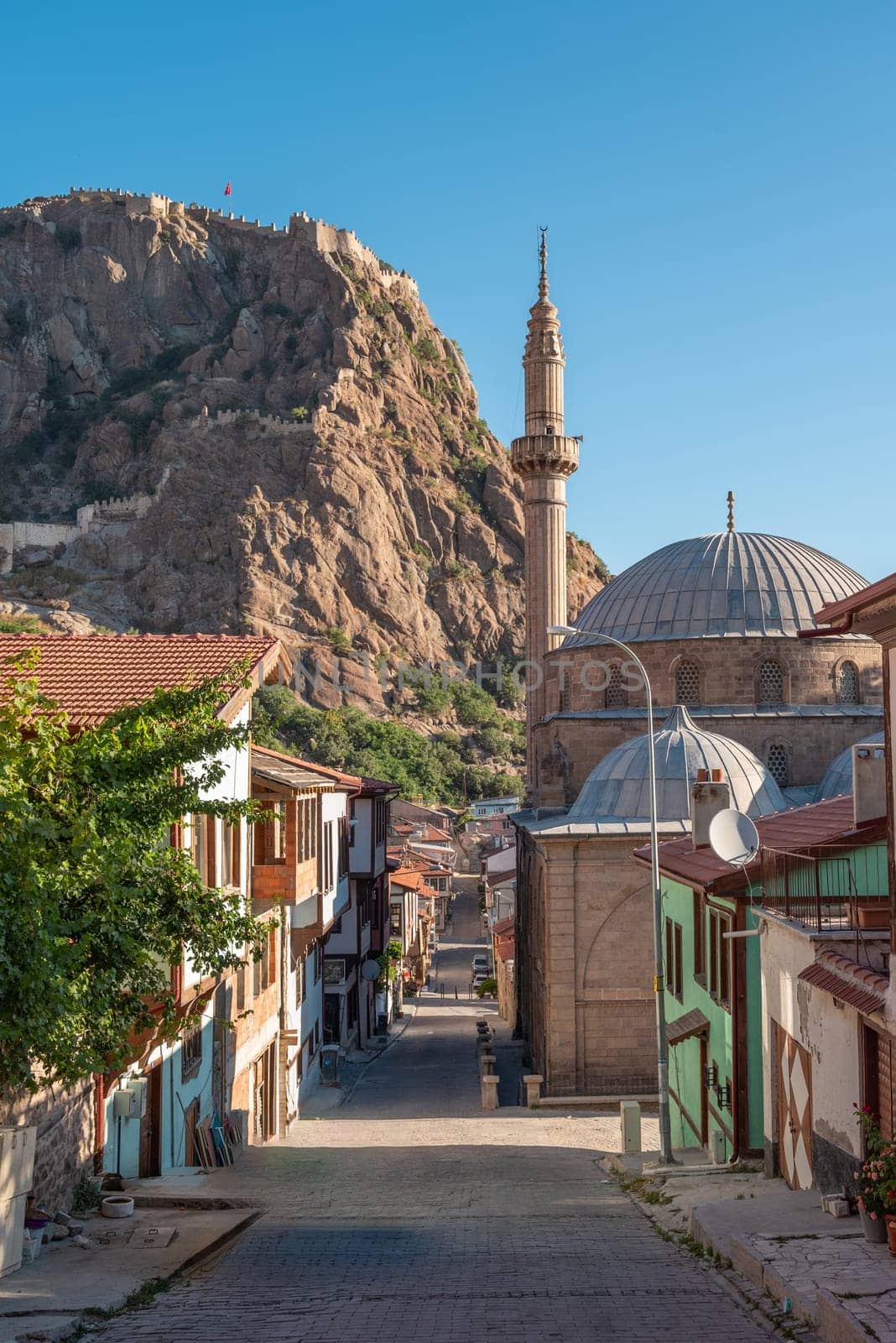 Traditional Turkish Ottoman houses in Afyonkarahisar Turkey. Afyon Castle on the rock and Mevlevihane Museum in front of it by Sonat