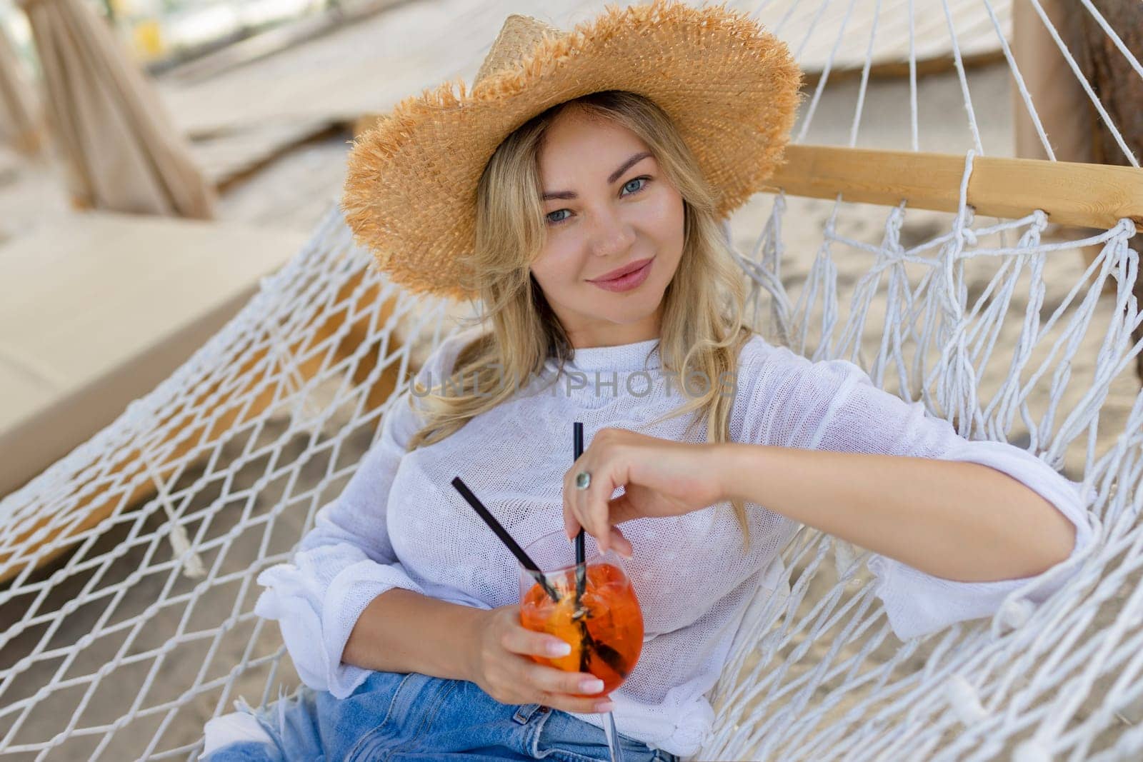 woman with cocktail relaxed in hammock.