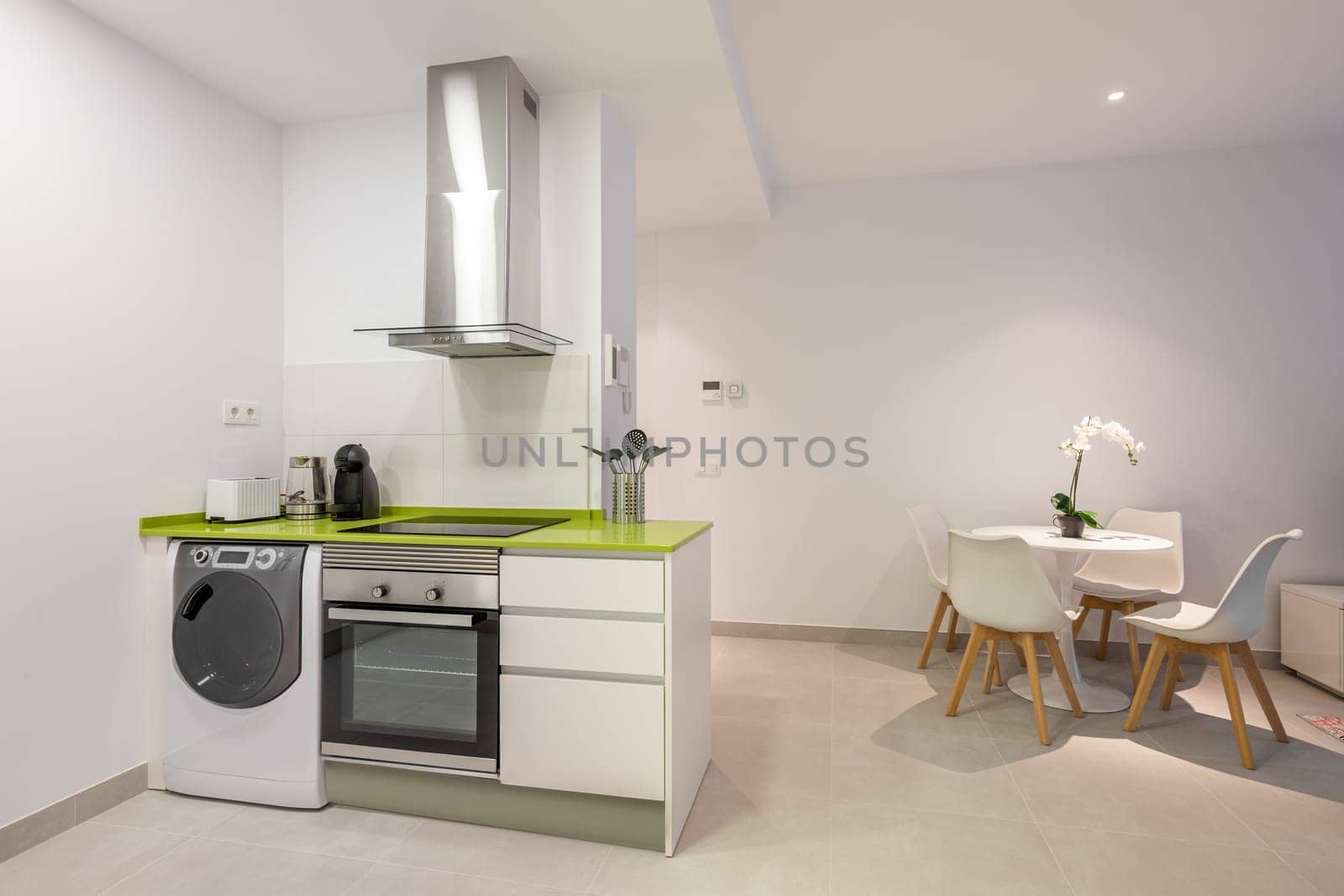 Horizontal shot stylish green and white kitchen with high-tech appliances and modern furniture. Young small family kitchen concept.