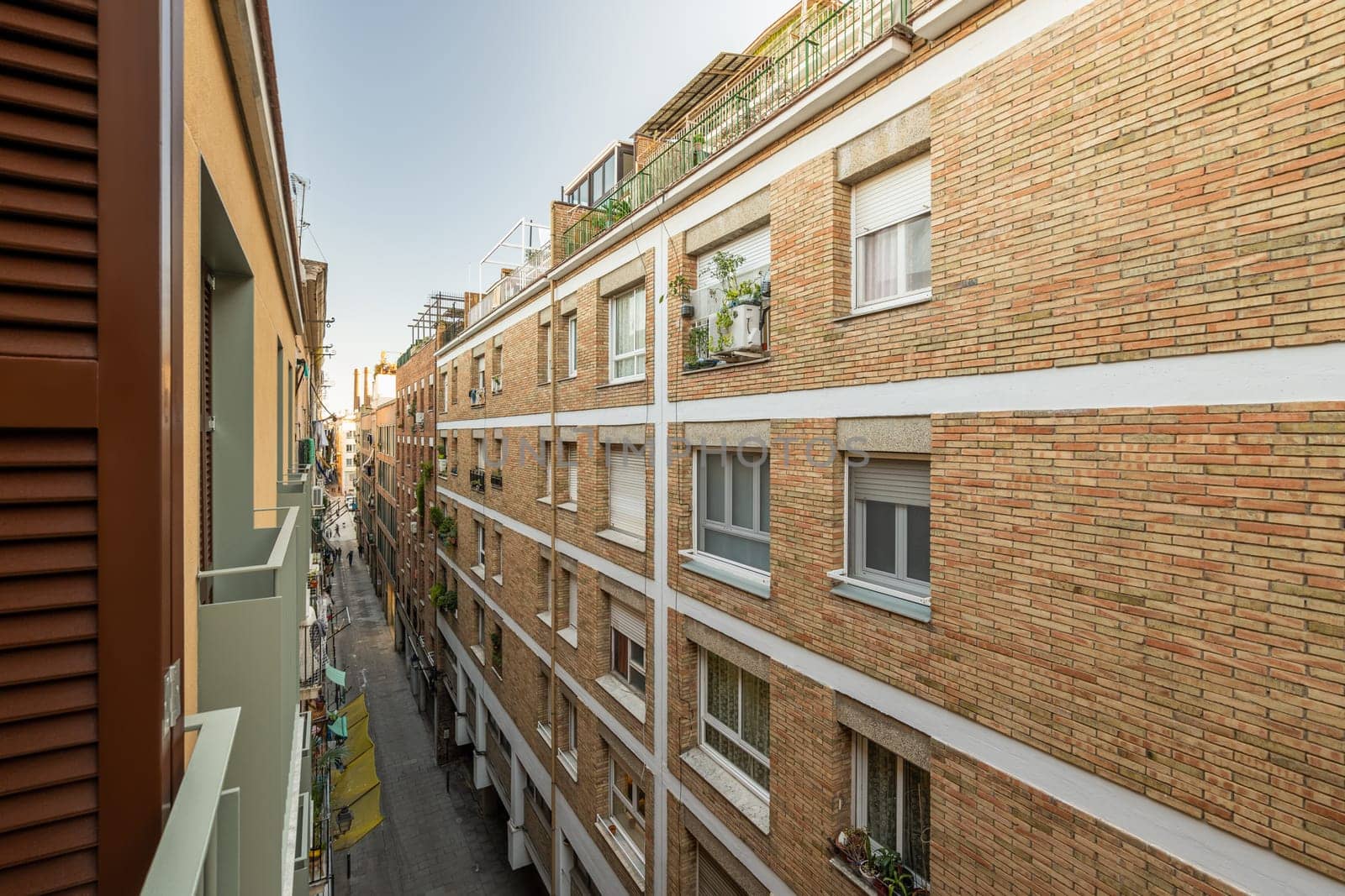 View from the balcony of a narrow barcelona street among modern brick houses. The concept of modern Spanish architecture. Tourist Europe by apavlin