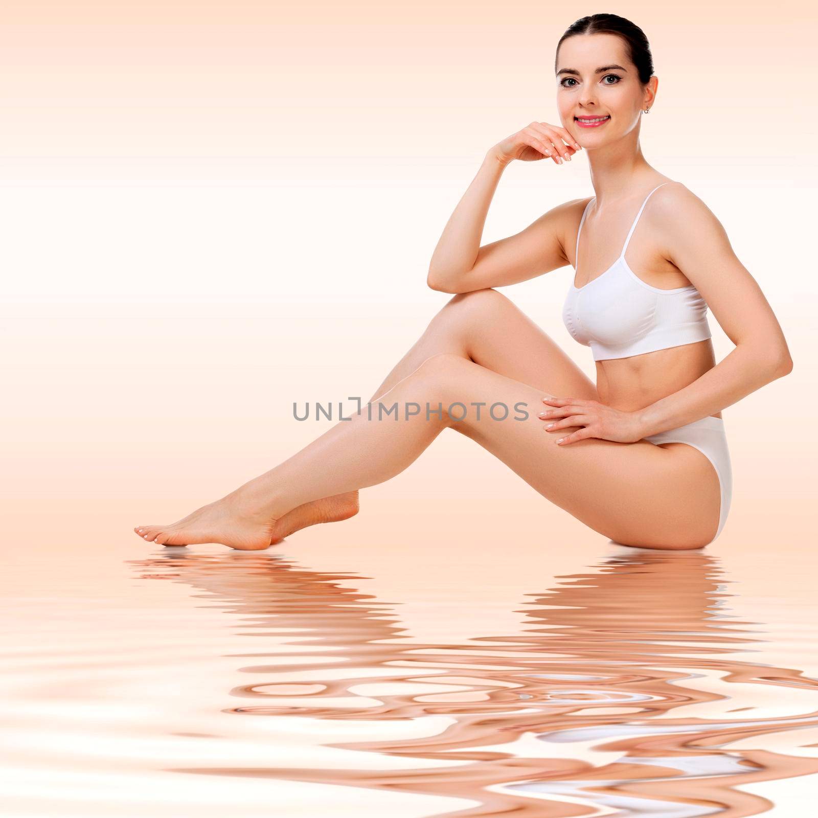 Wellness and beauty concept, beautiful slim woman in white underwear sitting on a floor and smiling to you