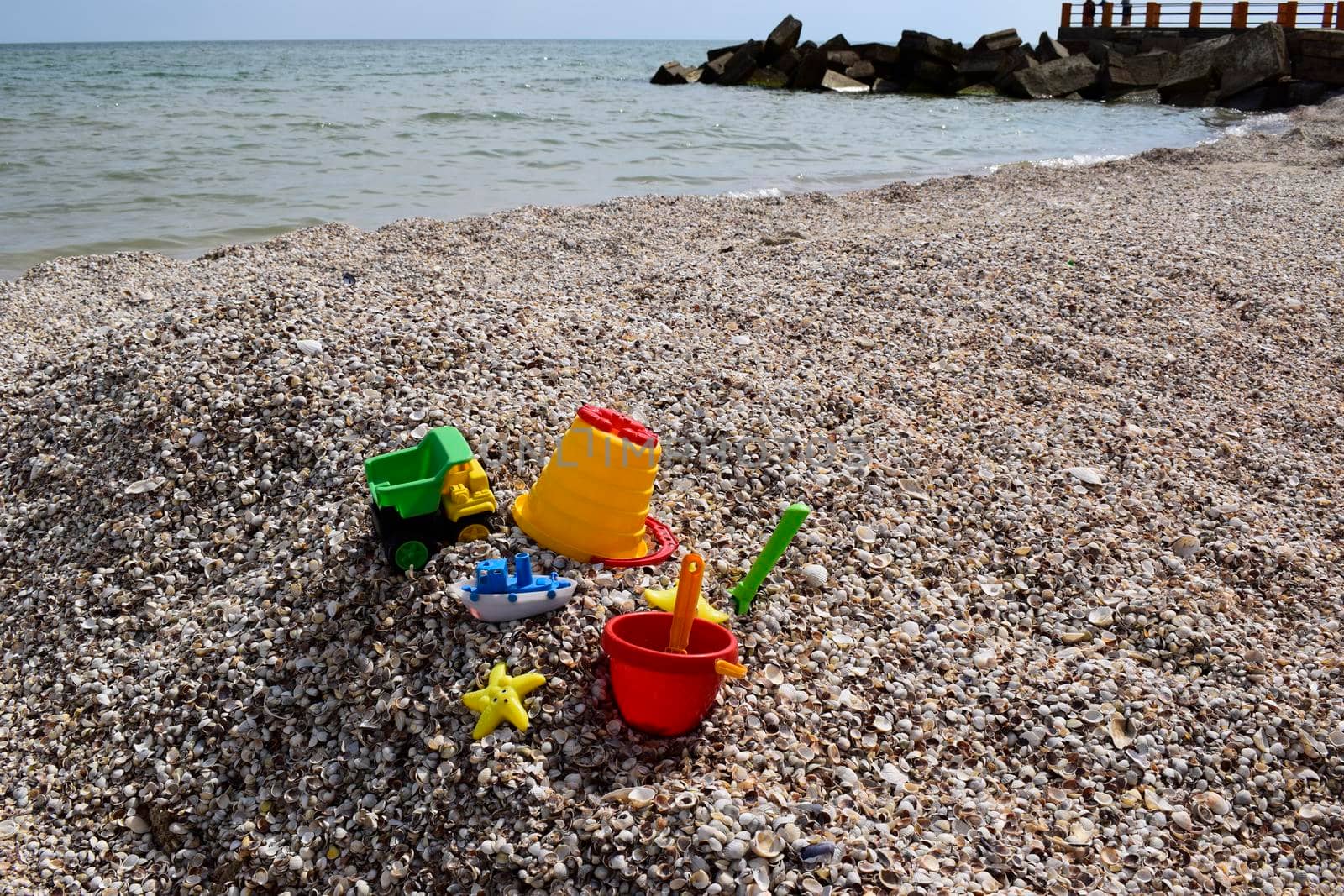 Child's bucket, spade and other toys on tropical beach against sea and blue sky.