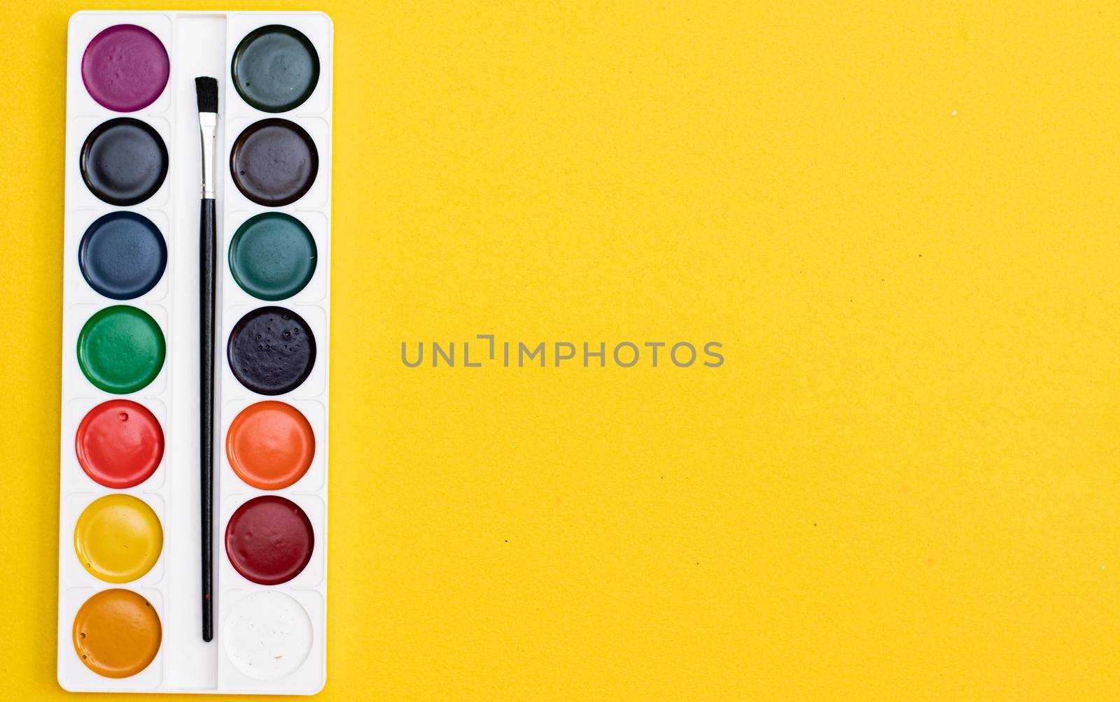 Watercolor paints on a yellow background . Paints for drawing. Hobbies and recreation. Office supplies. School supplies. Copy Space