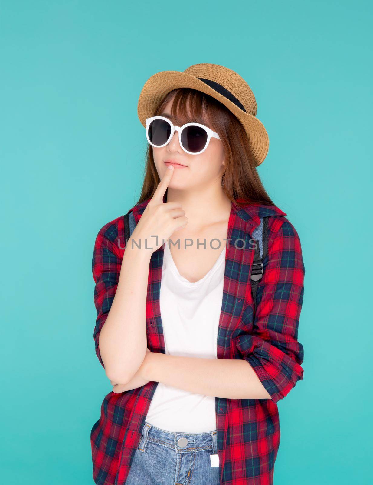 Beautiful portrait young asian woman wear sunglasses and hat having backpack smile confident enjoy summer holiday isolated blue background, tourist model girl thinking idea planning travel concept. by nnudoo