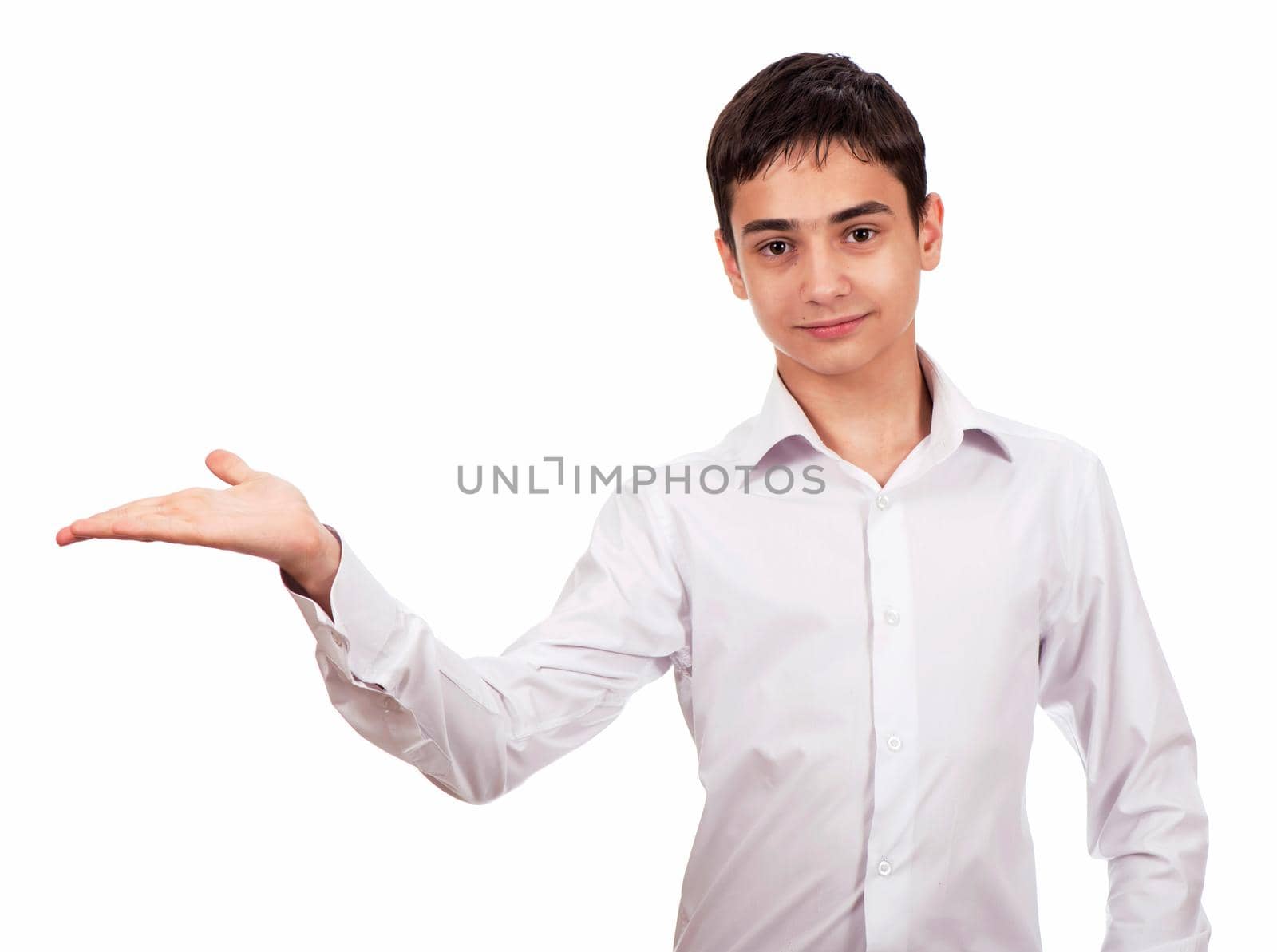 Smiling guy in white clothes on a white background looks at the camera and shows an empty palm. Cheerful young man in white shirt shows on blank space by aprilphoto