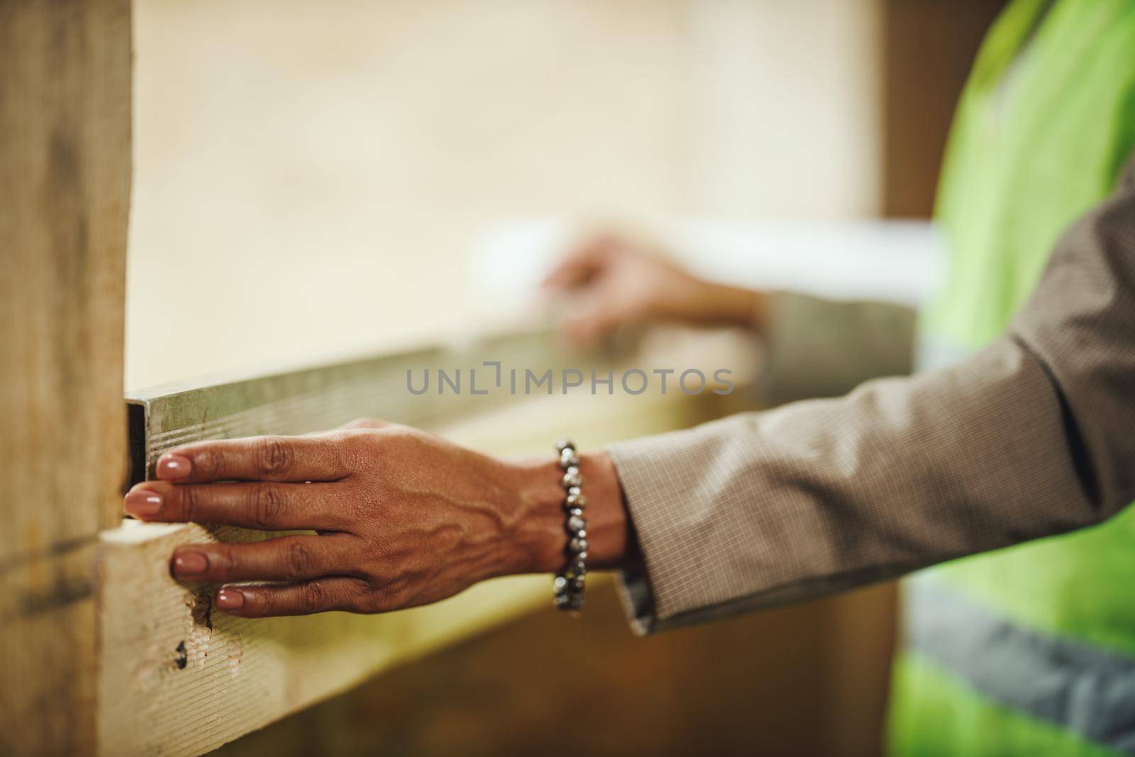 Croped shot of an African unrecognizable female architect using level on window to check new wood house.