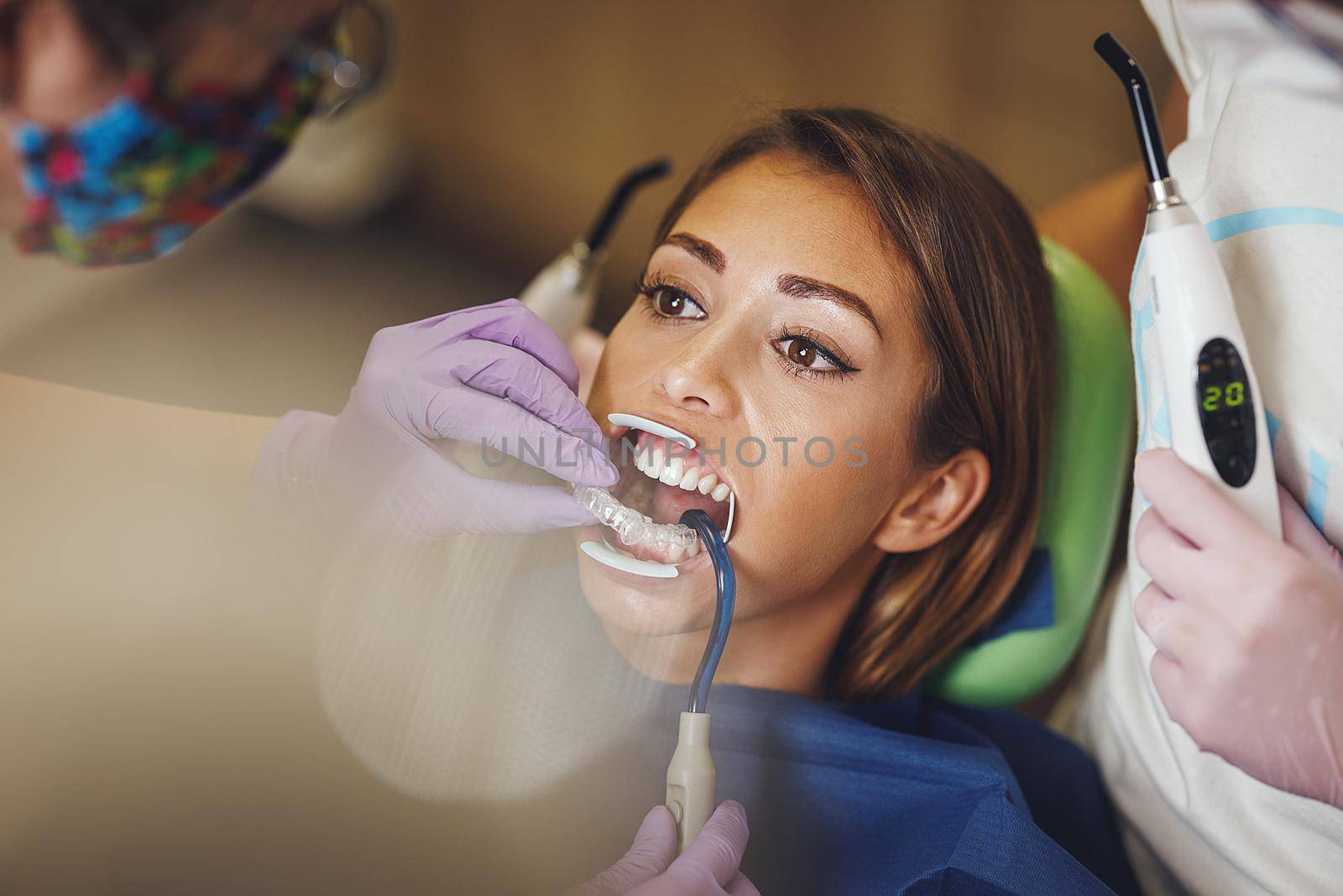 Shot of a beautiful young woman is at the dentist. She sits in the dentist's chair and the dentist sets braces on her teeth putting aesthetic self-aligning lingual locks.
